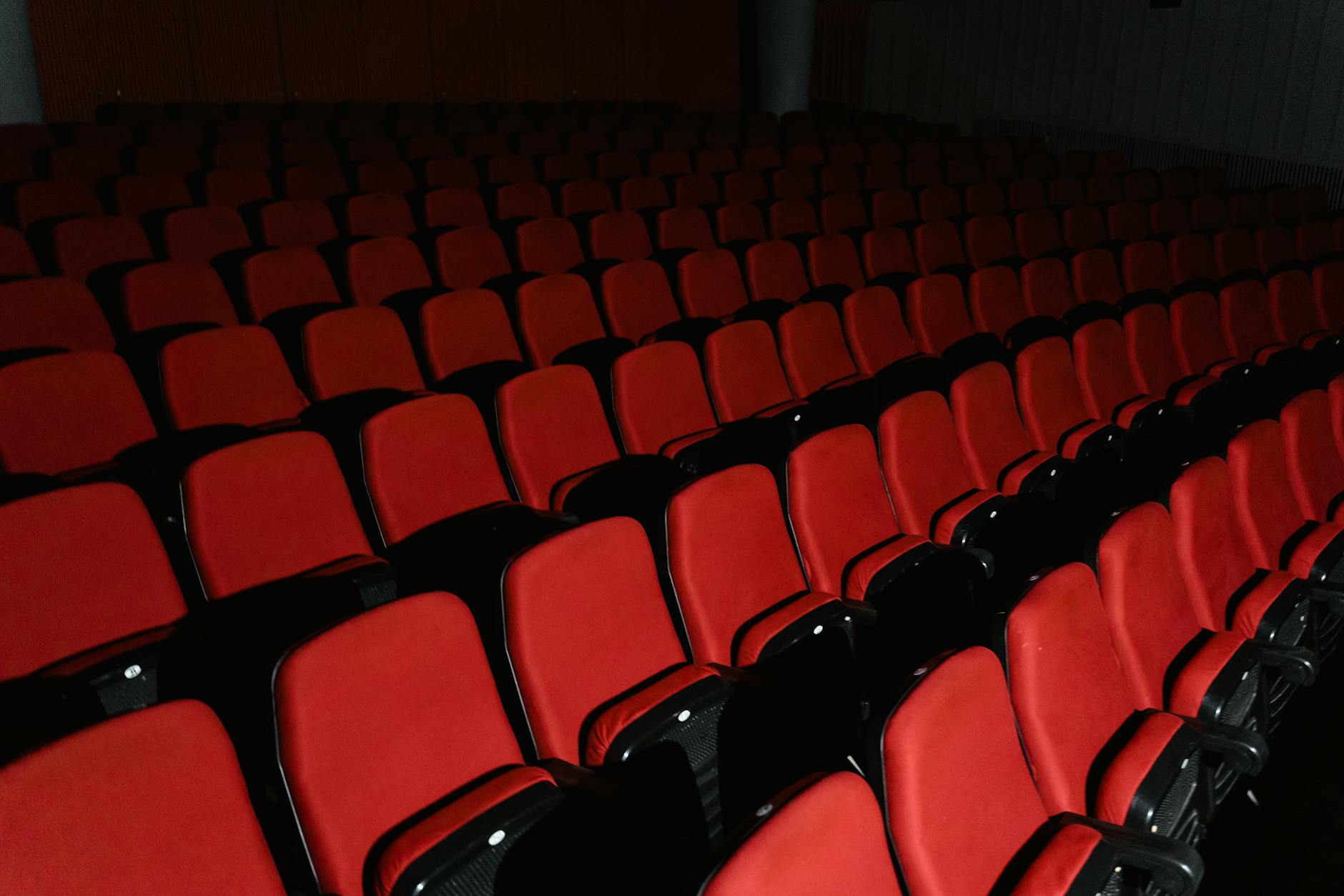 paese di Sognatori — A view of empty red theater seats arranged in rows inside a cinema hall.