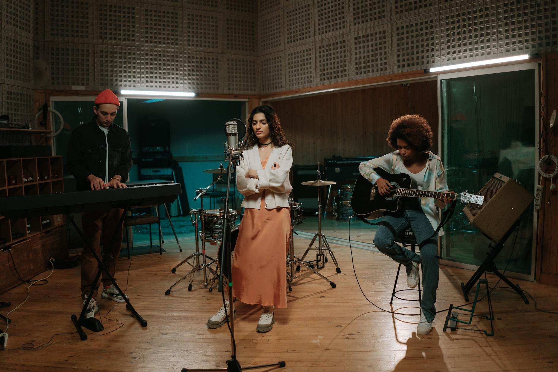 carriera di Arisa — A diverse group of musicians rehearsing in a modern studio with various instruments, creating live music.