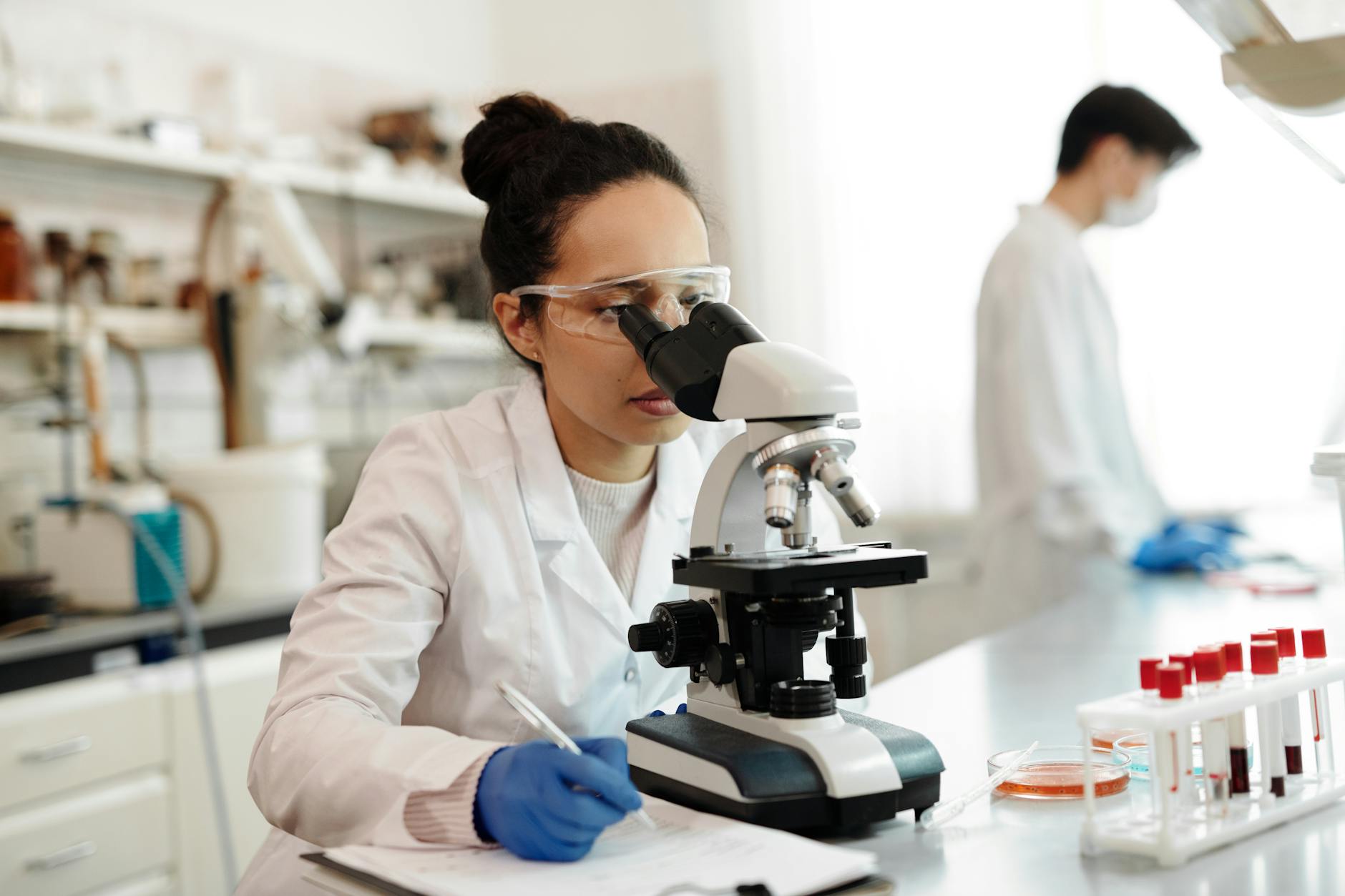musica nel DNA — A scientist in a lab coat using a microscope in a modern laboratory setting.