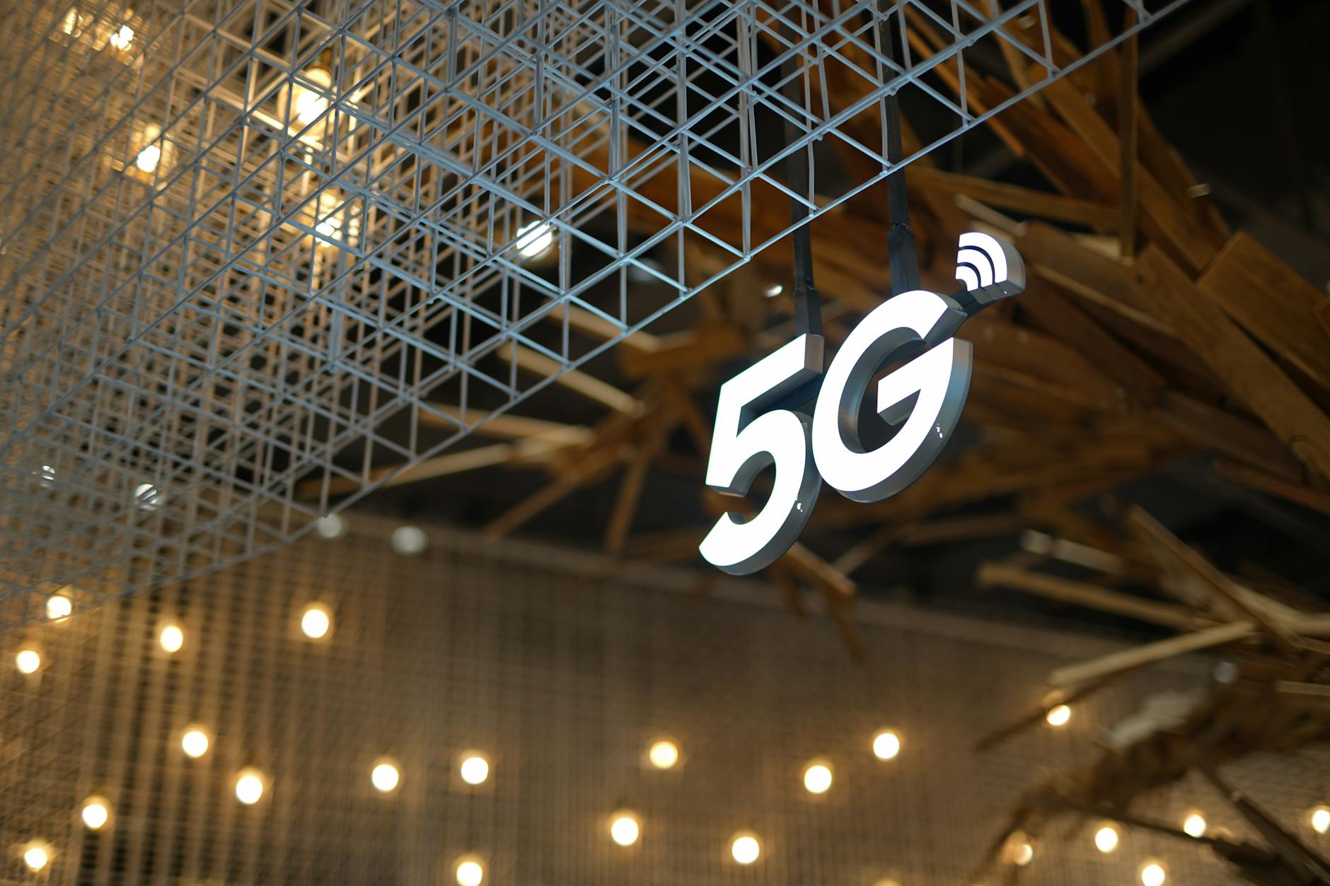 Alleanza 5G — Illuminated 5G sign with modern geometric ceiling and warm lighting.