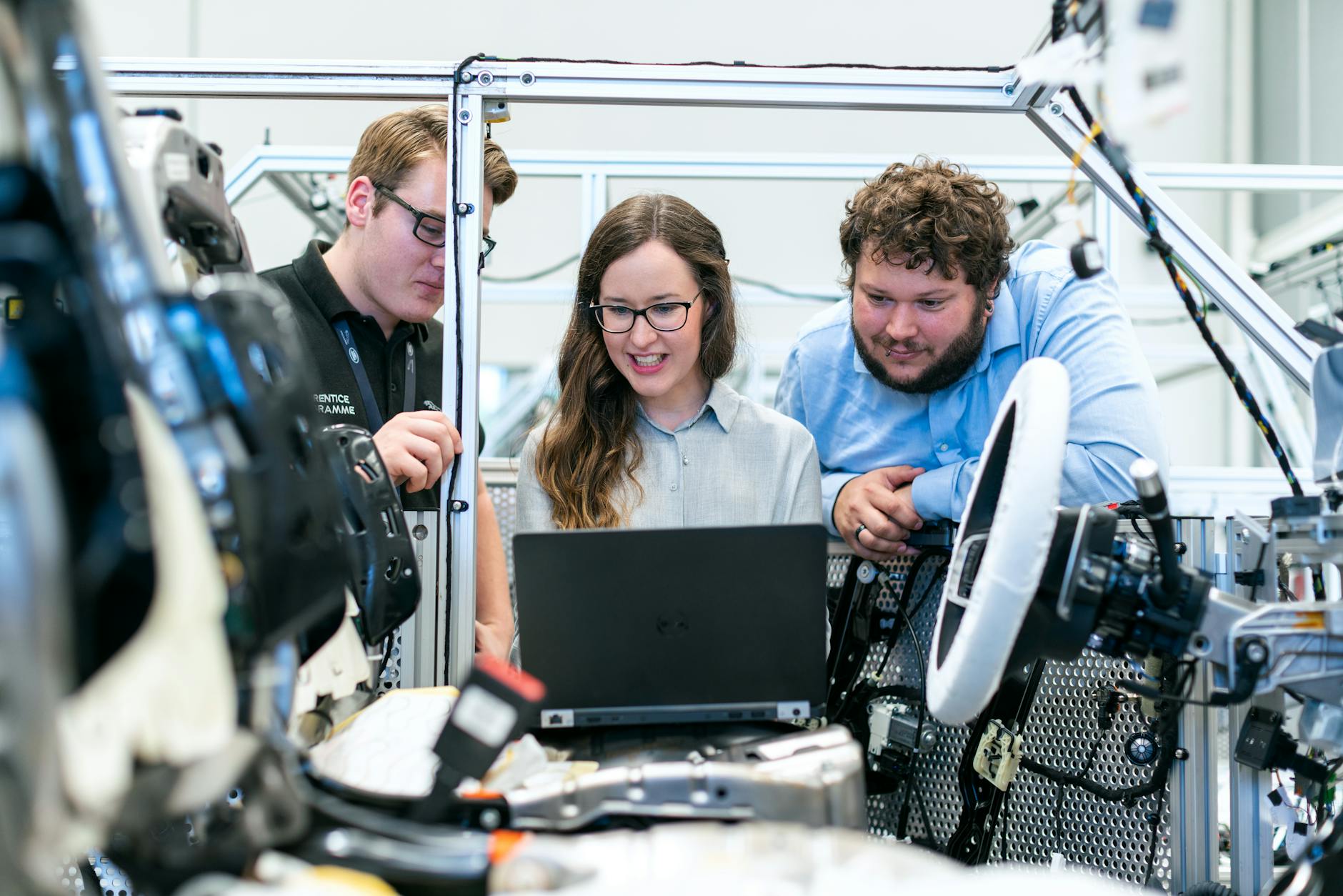 settore automotive digitale — Engineers collaborating on a car project in a modern automotive workshop using advanced technology.