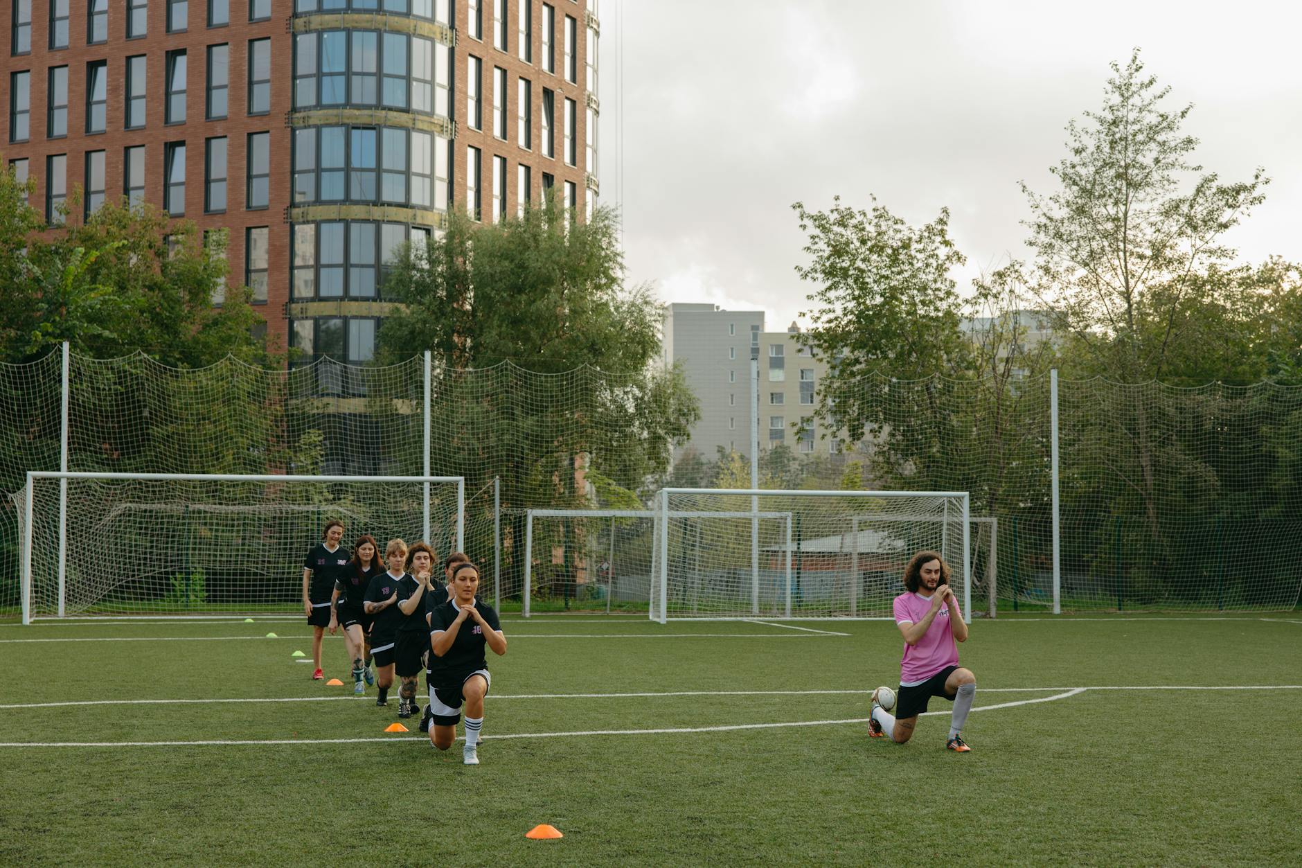 nazionale azzurra — A group of kids performing warm-up exercises with their coach on a soccer field.