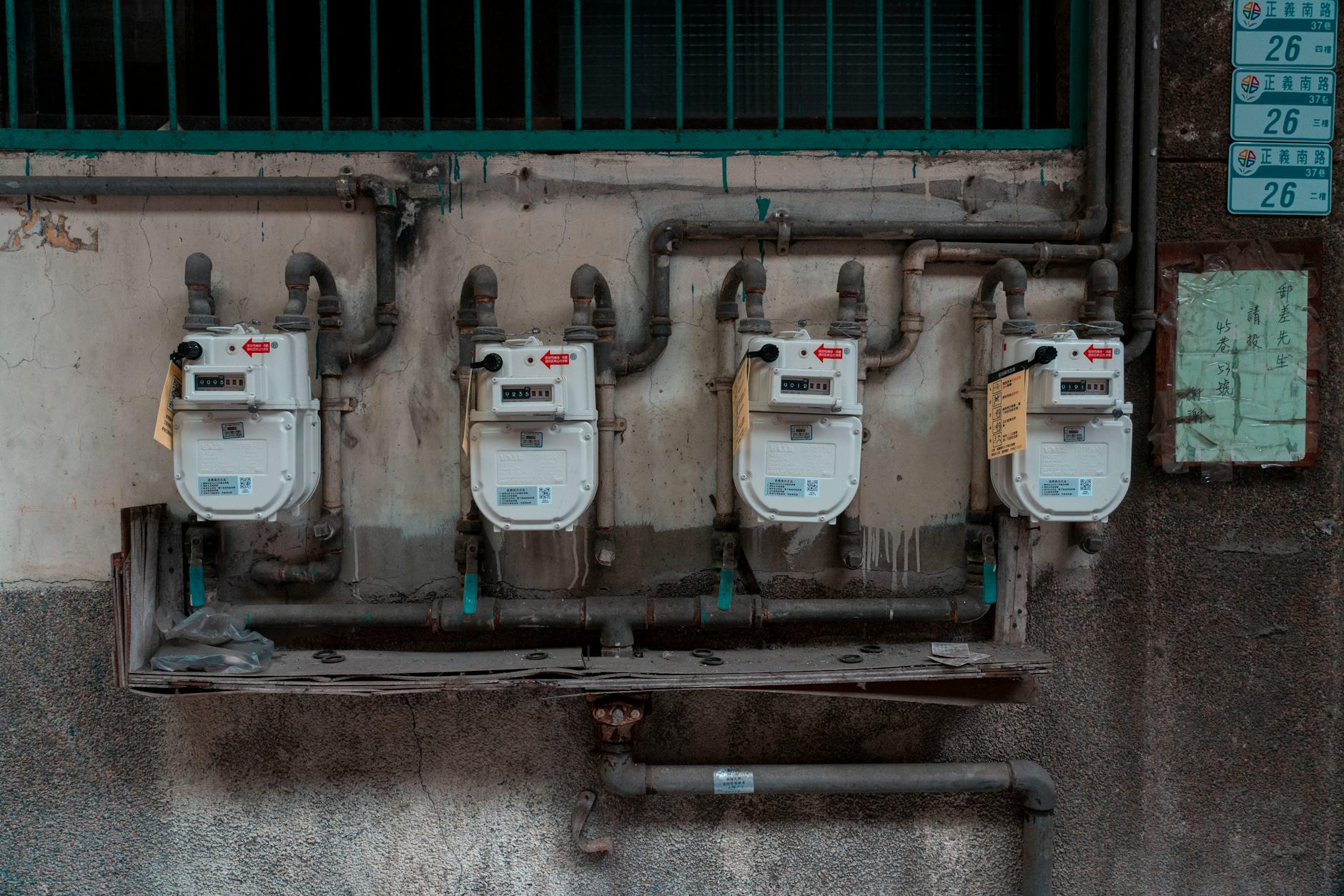 tariffe gas domestiche — Four gas meters mounted on an exterior wall, showcasing urban utility infrastructure.