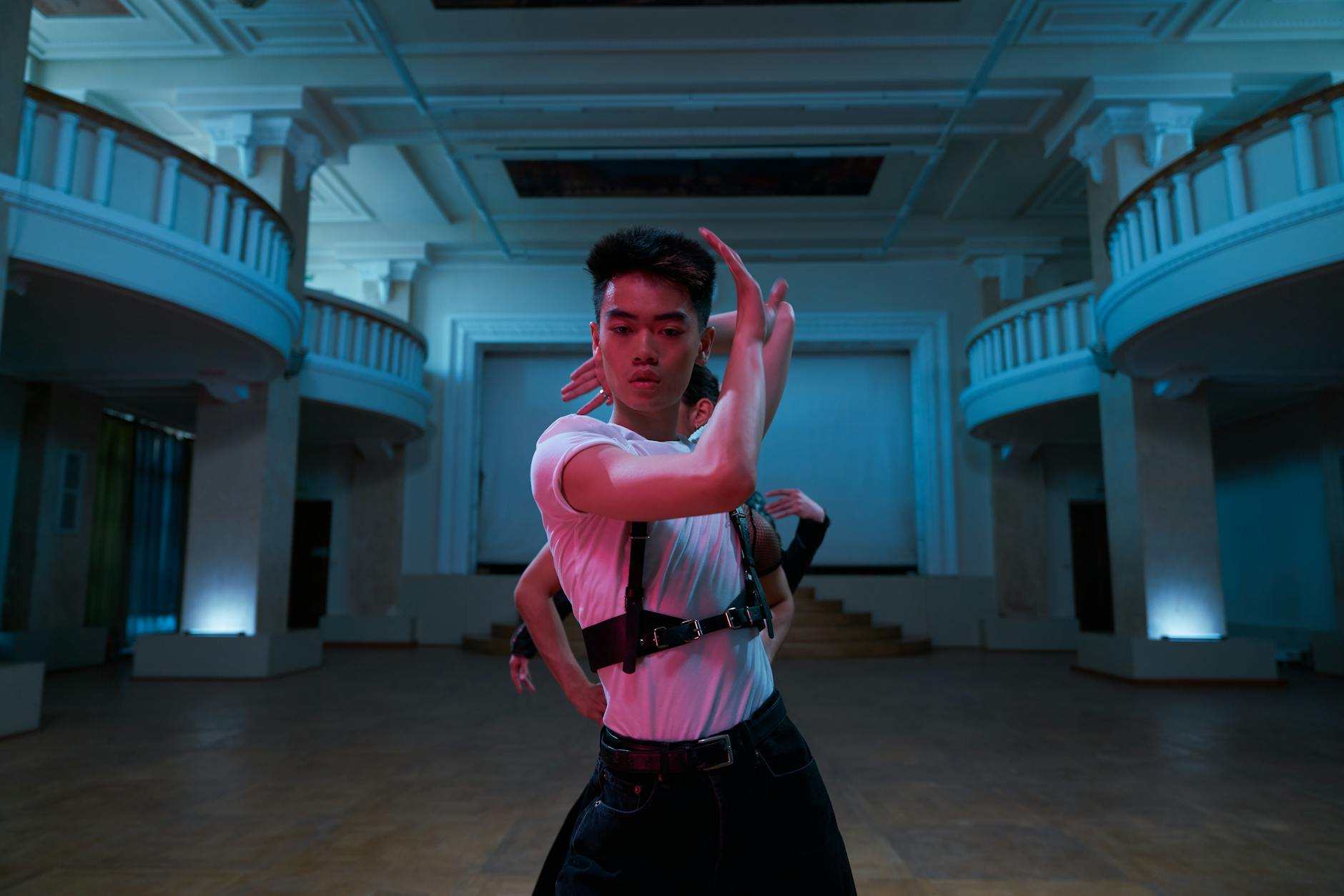 teatro italiano — A contemporary dancer moves expressively in a grand indoor setting under blue lighting.