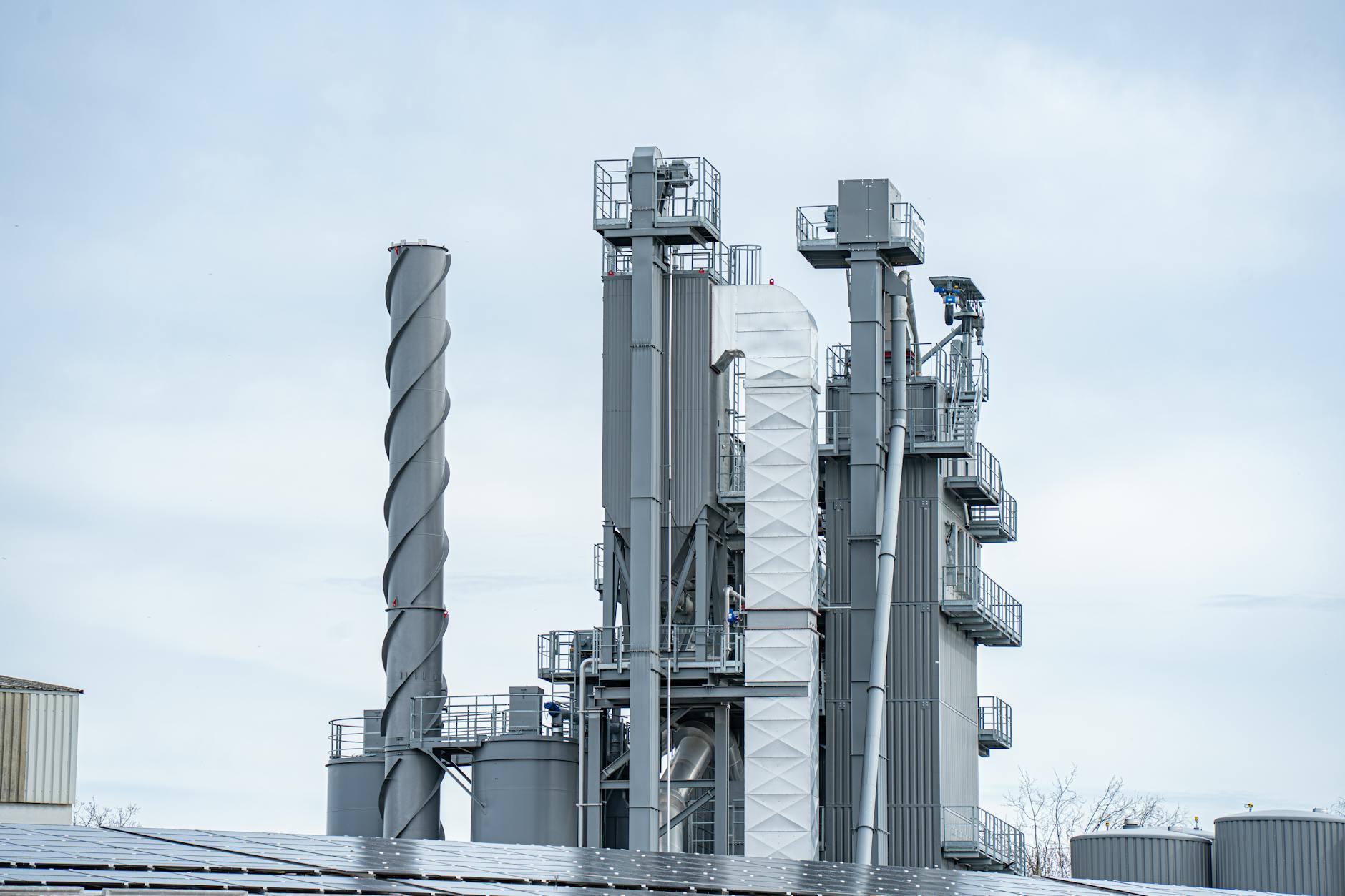 industria fertilizzanti — Gray industrial chimneys rise above factory buildings against a clear sky, showcasing modern industry.