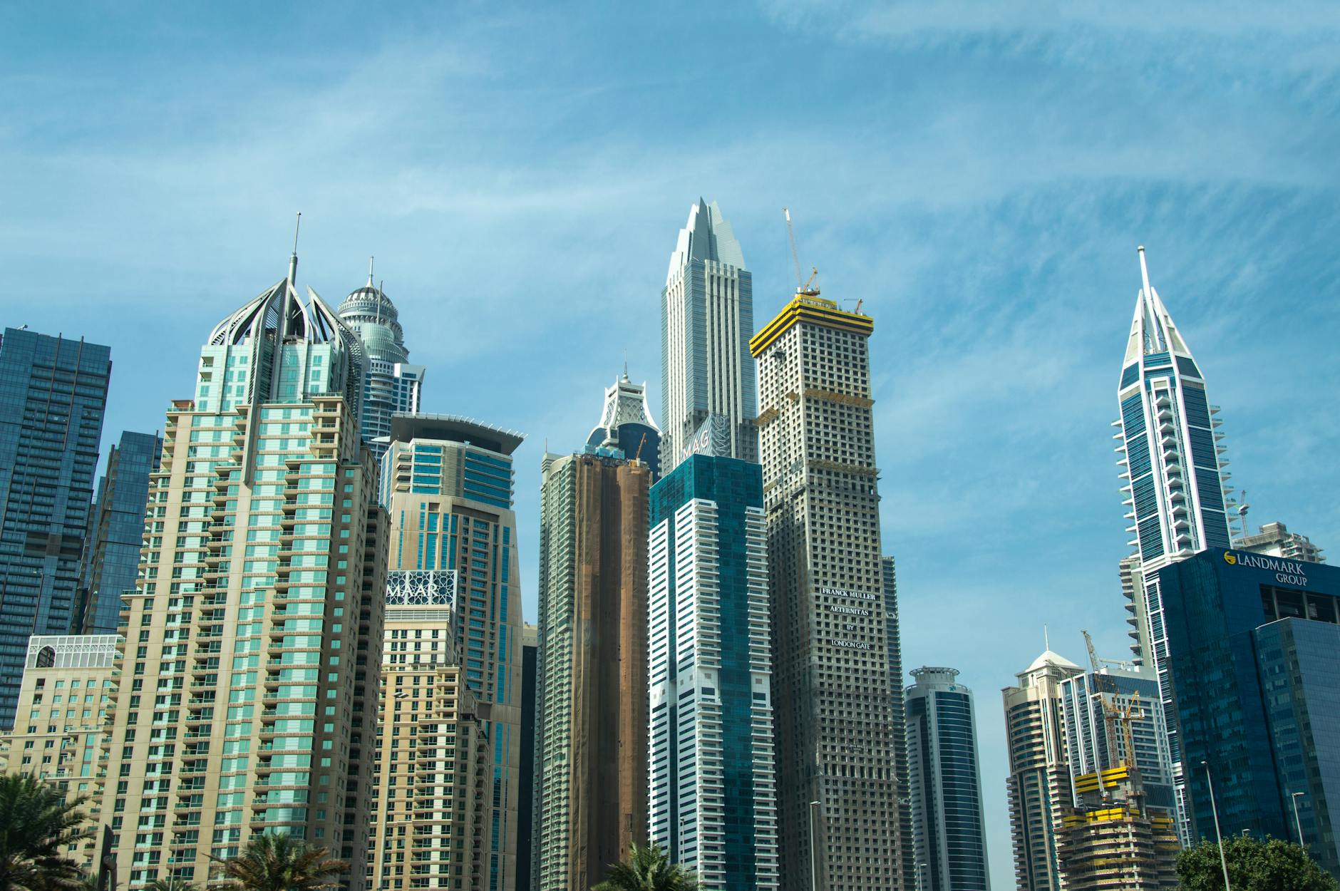Dubai economia — Modern skyscrapers against a blue sky in Dubai's bustling cityscape.