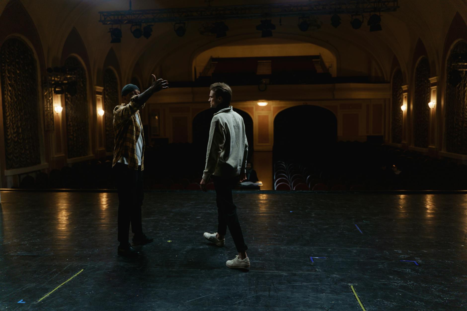 teatro e spettacolo dal vivo — Two men on stage practicing a scene in an empty theater, demonstrating drama and performance art.