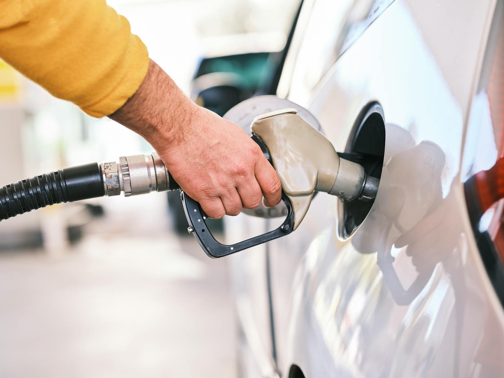 tassa sugli extraprofitti — Close-up of a person refueling a car with a gas nozzle at a station.