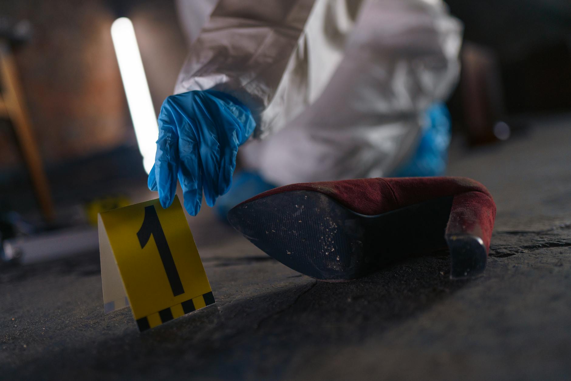 omicidio Sciorilli — Crime scene investigation with shoe as evidence marked with number one and forensic glove.