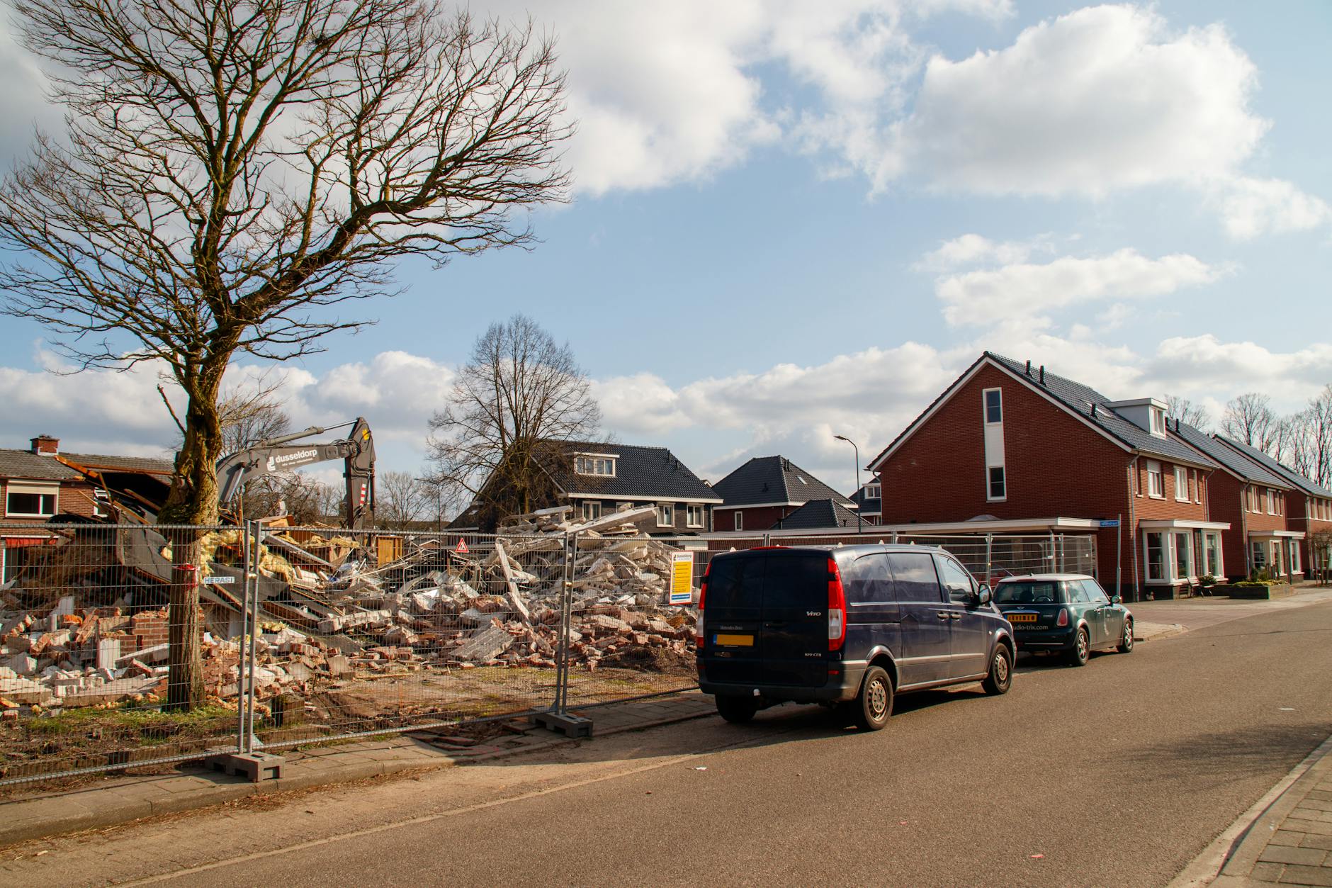 acquisto immobiliare in zone riqualificate — Residential neighborhood with a building under demolition and construction equipment in view.
