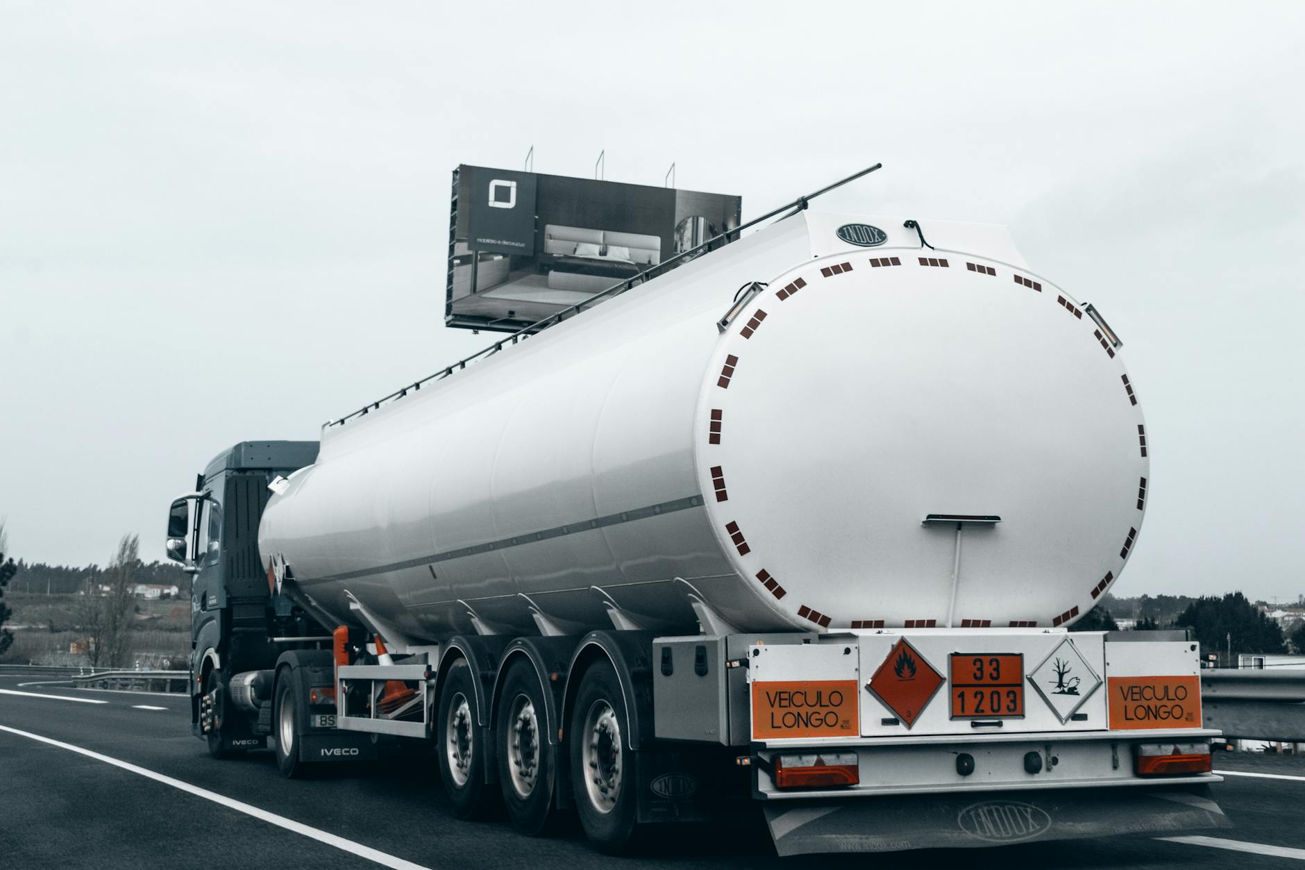 crisi carburante diesel — Rear view of a large tanker truck transporting fuel on a highway, emphasizing logistics and transportation.