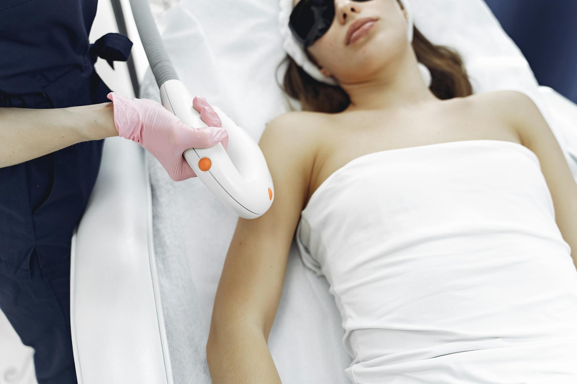 epilatori luce pulsata — From above of unrecognizable cosmetologist in uniform and latex gloves using modern equipment for cosmetic services in contemporary salon
