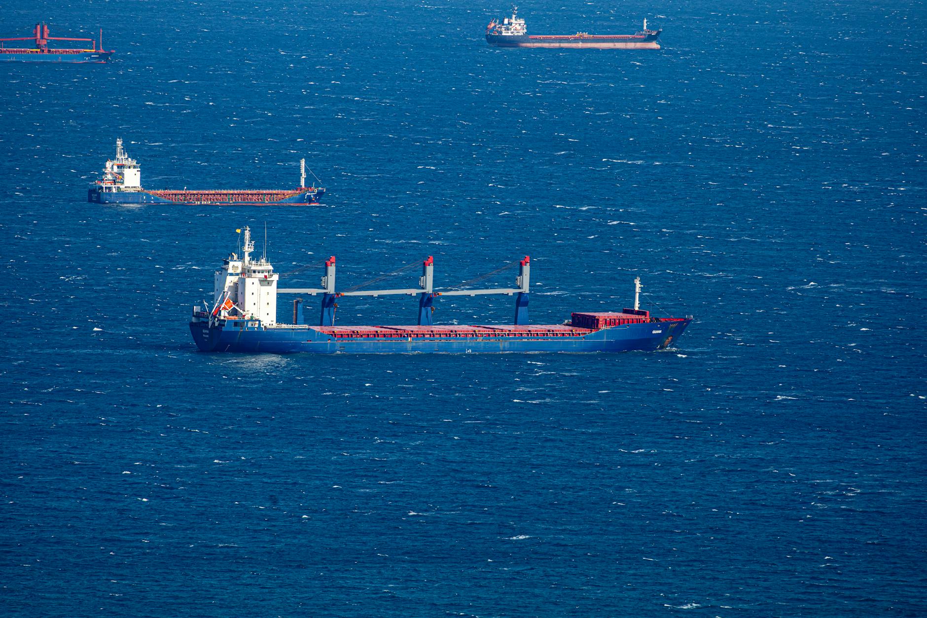 accordo commerciale egiziano russo — Aerial view of multiple cargo ships navigating through the vast blue ocean, capturing maritime commerce.