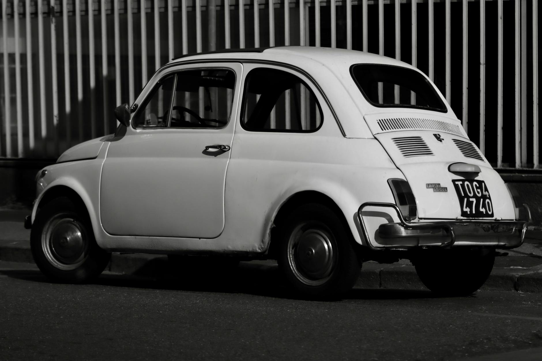 elettrificazione Fiat 500 — A classic Fiat 500 in monochrome, parked against an urban backdrop in Turin, Italy.