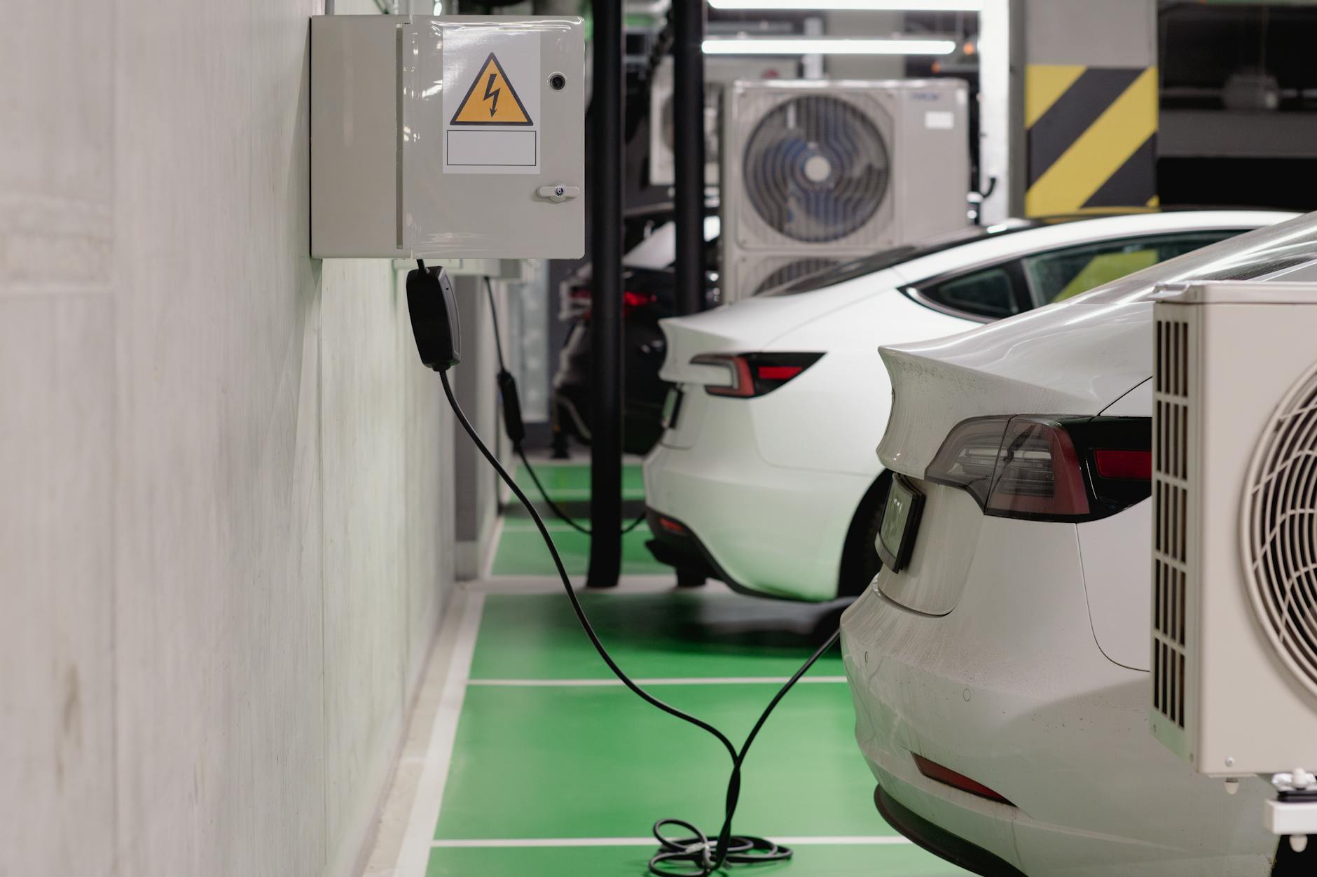 industria auto europea — Electric vehicles charging at an indoor station in a modern underground garage.