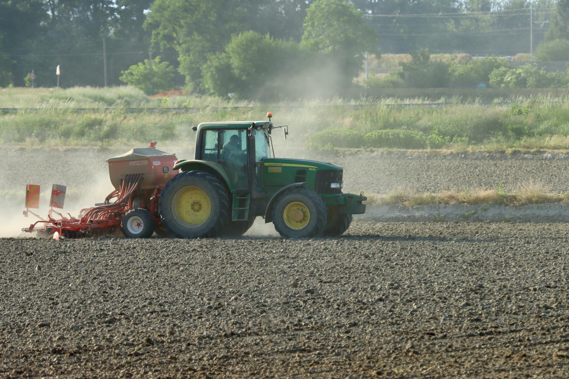 piano Coltiva Italia — A tractor plowing a field during daytime in Novara, Italy, showcasing modern farming techniques.