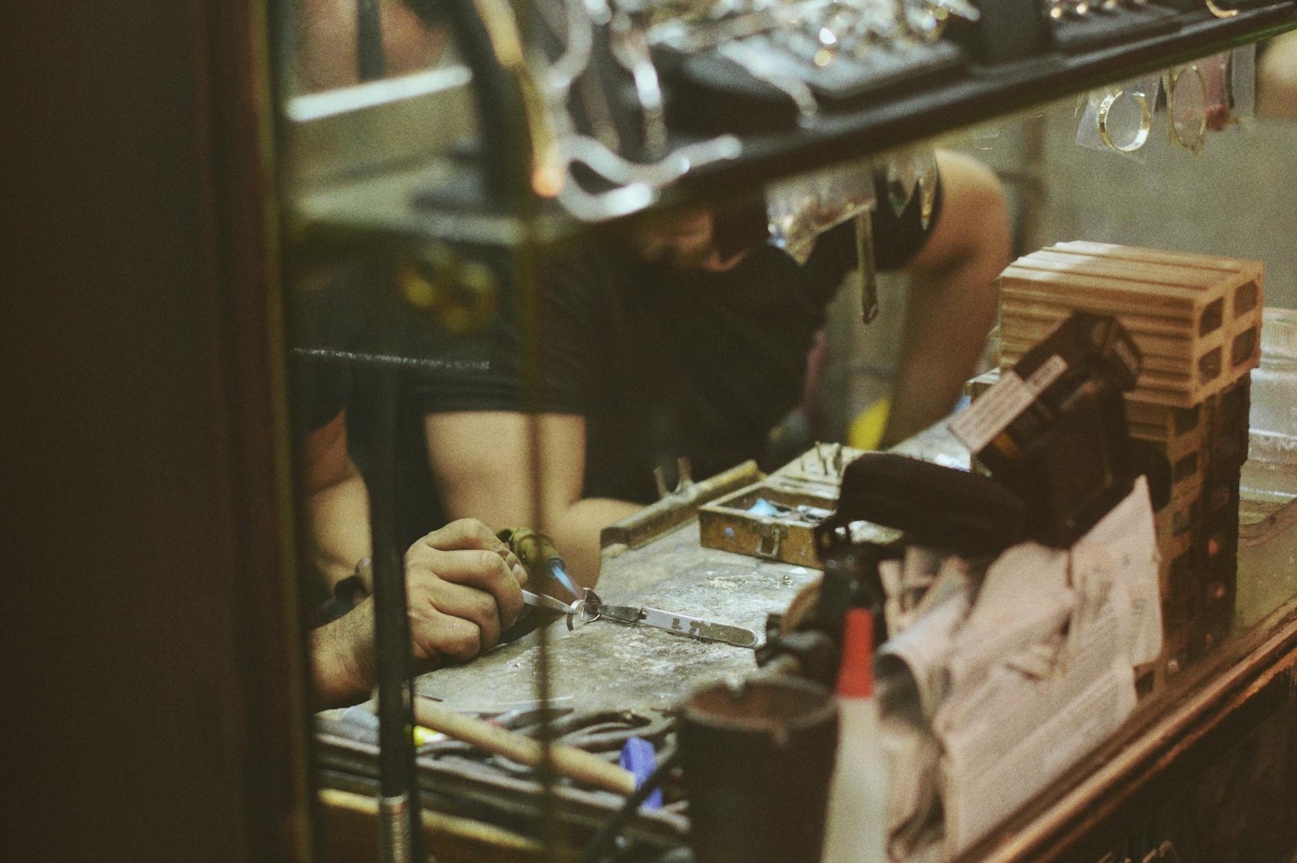 oreficeria italiana — Close-up of an artisan at work in a jewelry workshop, focusing on craftsmanship and tools.