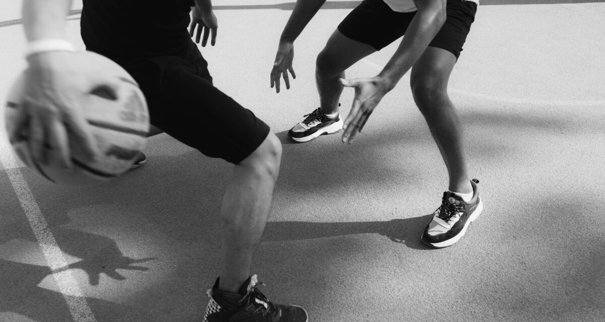 Monochrome image capturing intense basketball action and dribbling on the court.