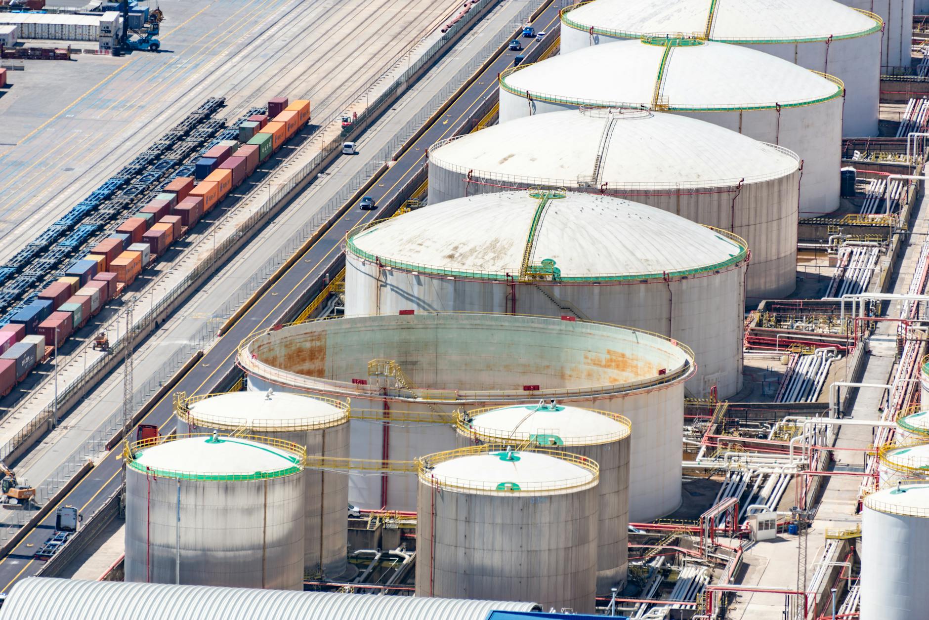 mercati petroliferi — Aerial shot of large oil storage tanks in an industrial district with adjacent railway tracks.