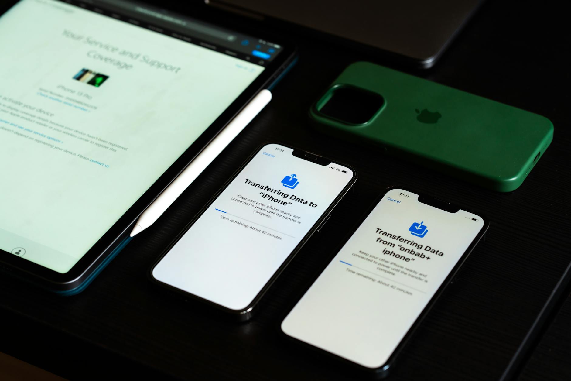 trasferimento dati smartphone — High-angle view of digital devices including iPhones and an iPad on a desk, showcasing data transfer.