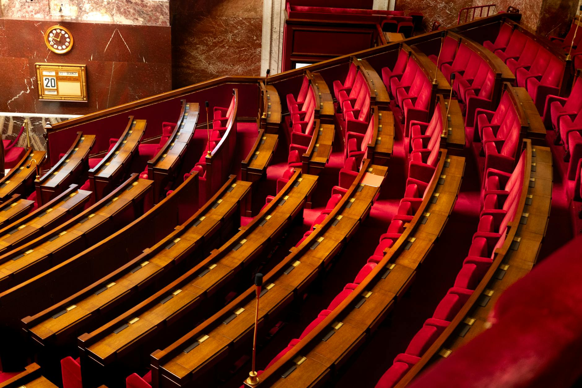 concordato preventivo — A luxurious interior view of a legislative chamber with curved red seating and wooden desks.