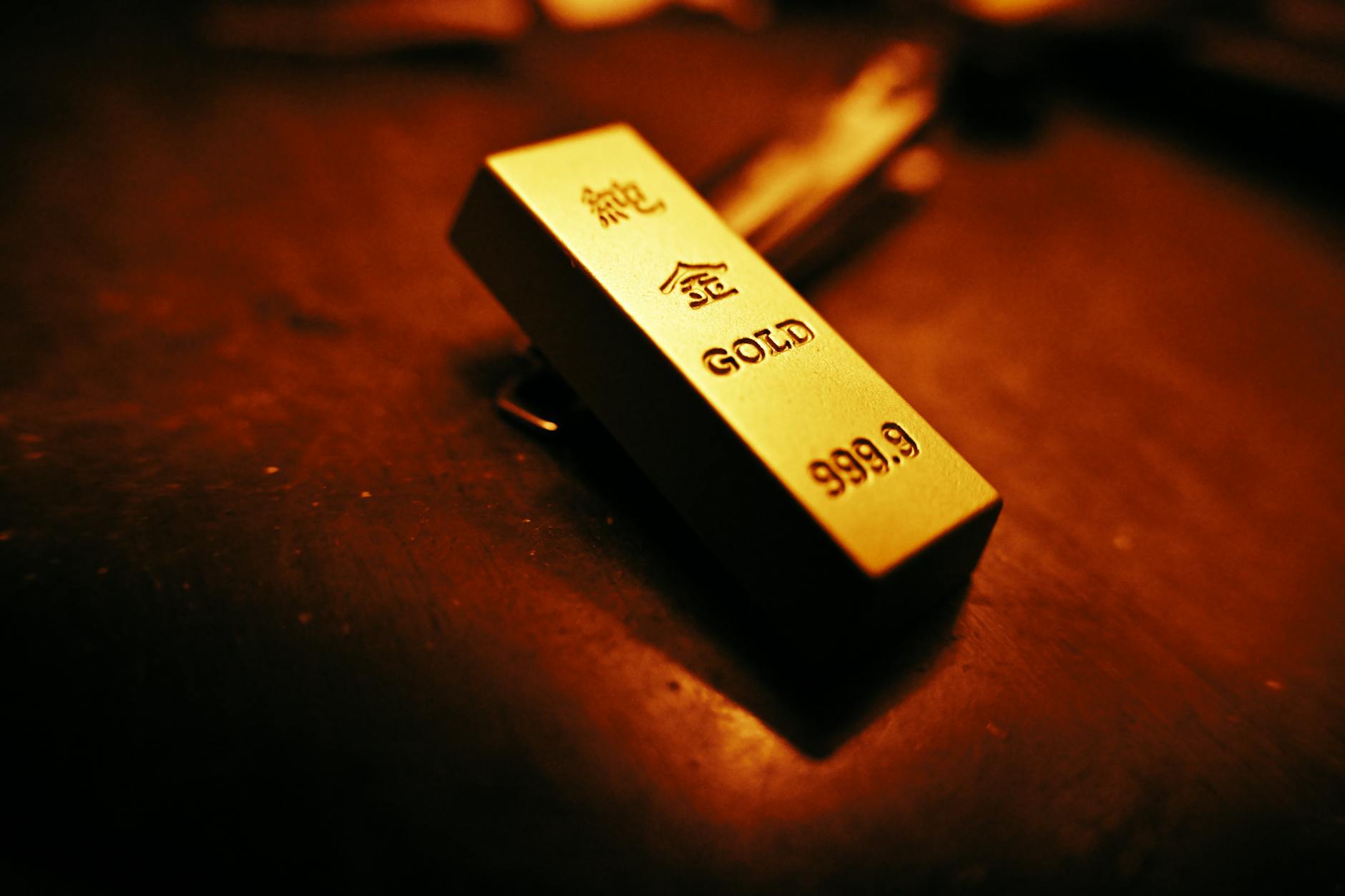 futures oro — A striking close-up of a gold bar showing inscriptions, captured with warm lighting.