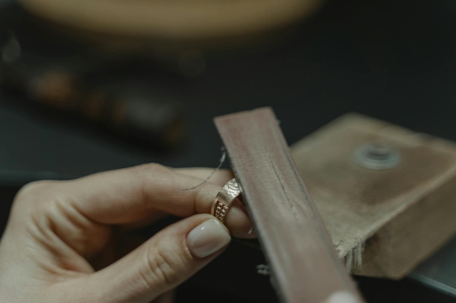 settore oreficeria italiana — Close-up of a craftsman polishing a gold ring using a tool, showcasing fine jewelry making.