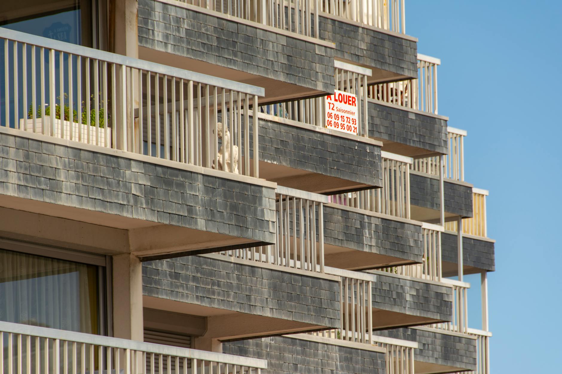 crisi abitativa europea — Close-up of modern building balconies with a visible rental sign.