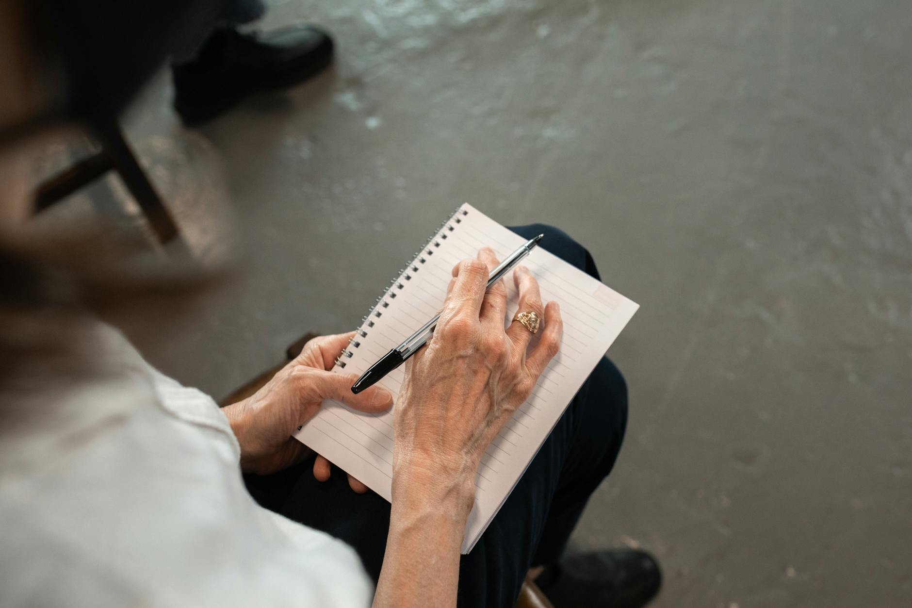 diagnosi precoce demenza — Close-up of senior hands with pen writing in a spiral notebook. Personal notes concept.
