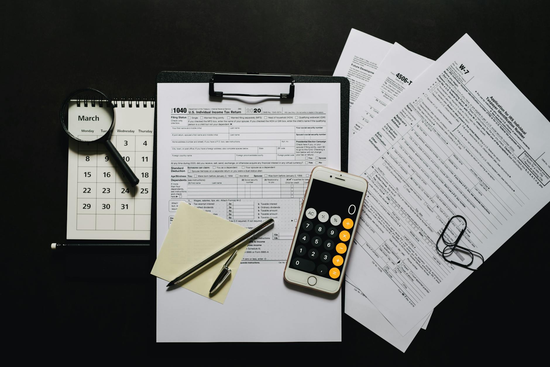 dichiarazione redditi 2026 — Top view of tax documents, calculator, magnifying glass, and calendar on a black surface.