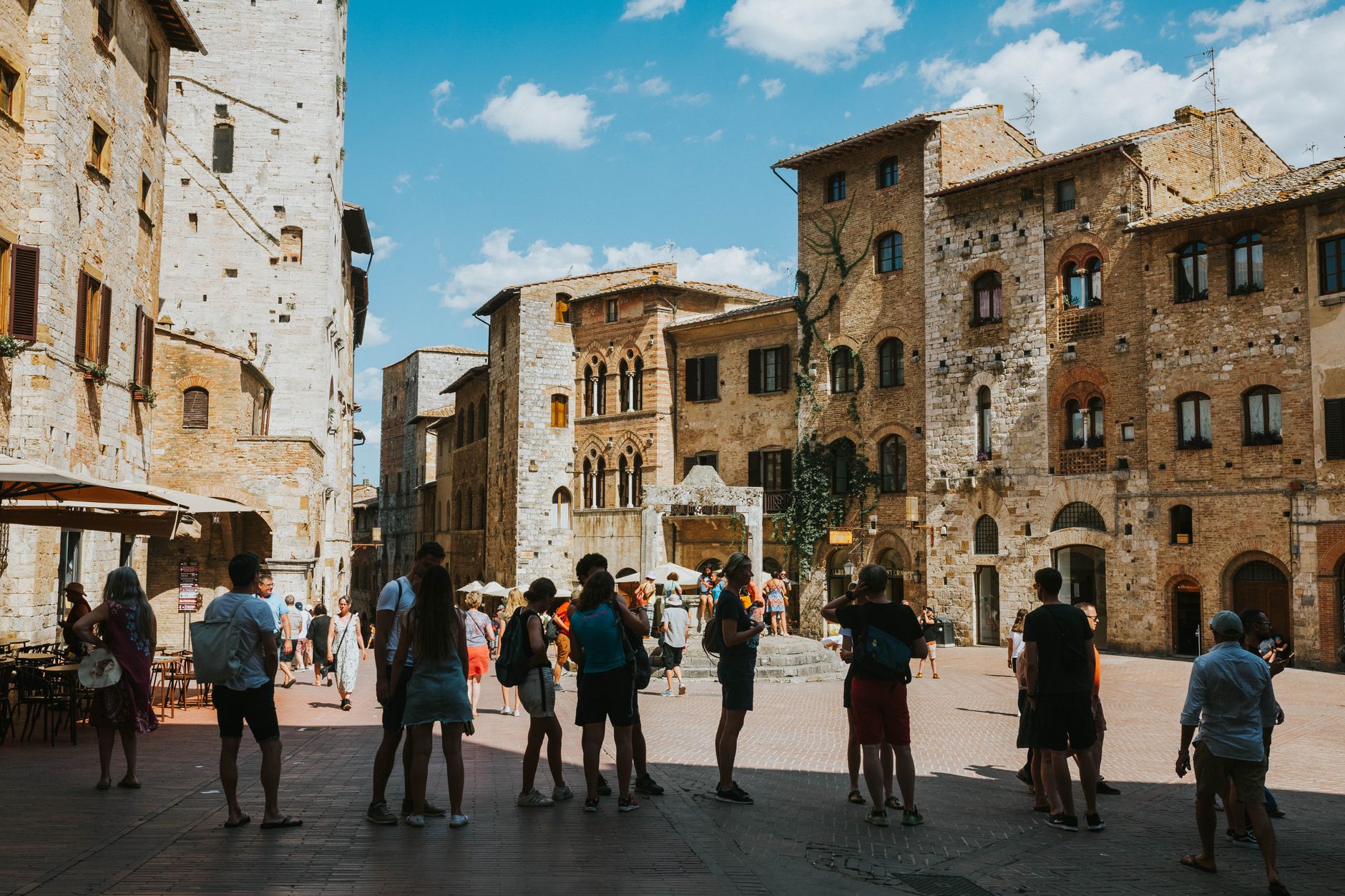 turismo Italia primo trimestre 2026 — Tourists gather at the medieval Piazza della Cisterna in San Gimignano, Tuscany, Italy.