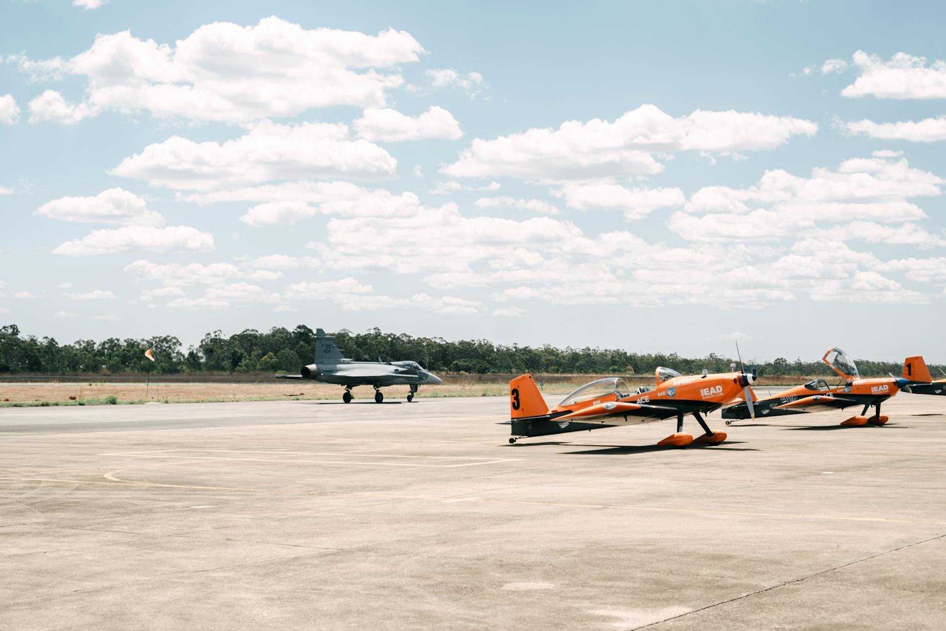 contratto Leonardo — Military jet and small propeller planes on a sunny runway.