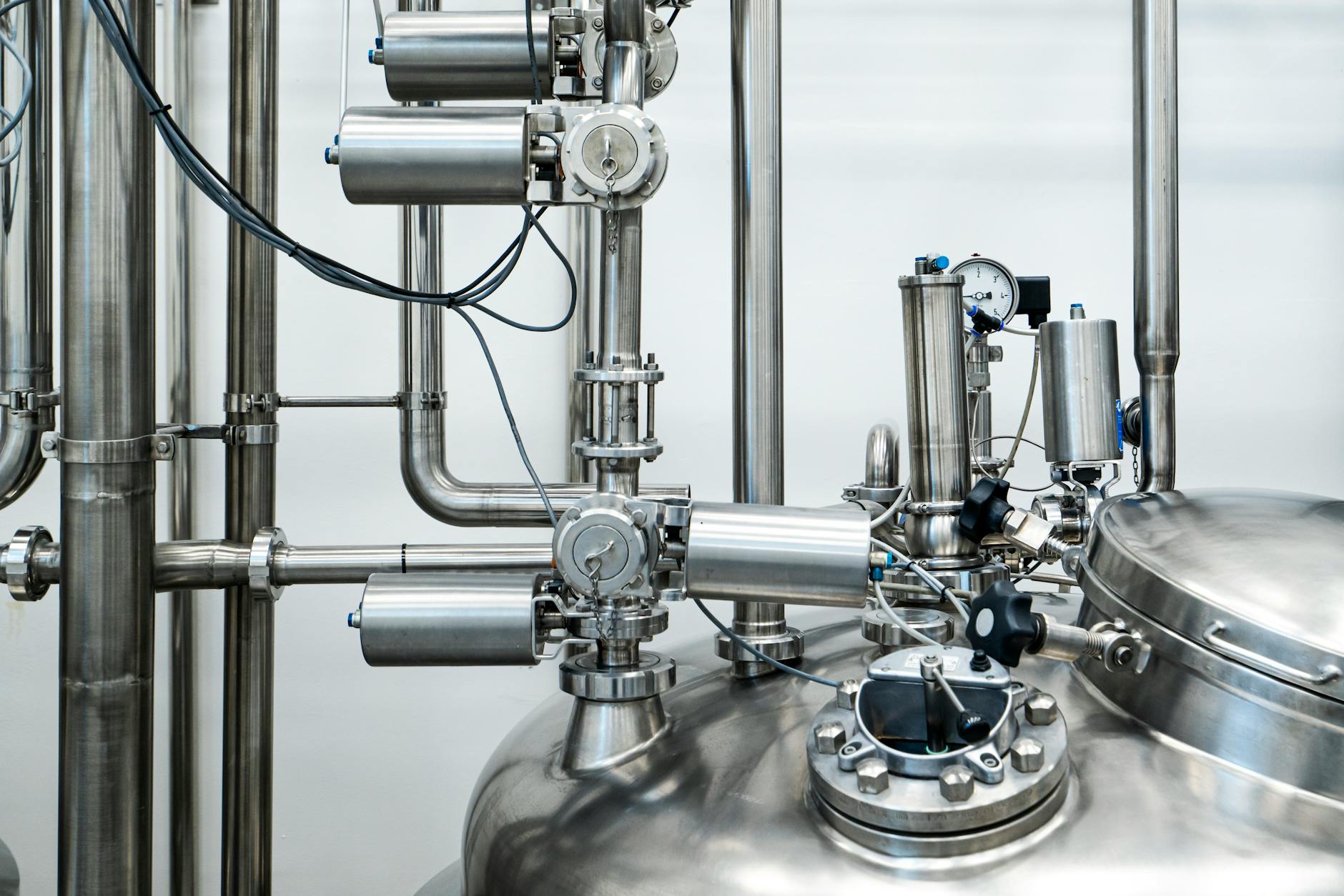 produzione industriale — Close-up of stainless steel machinery and pipes in an industrial setting, showcasing modern engineering.