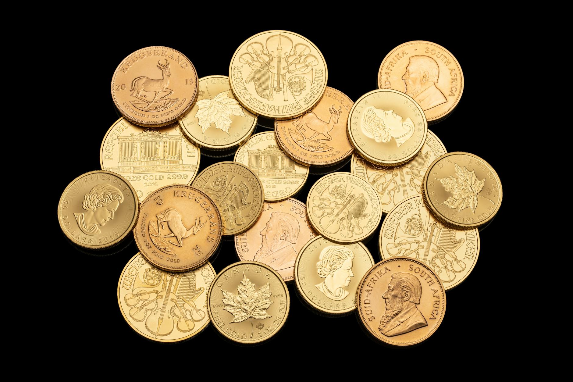 quotazioni dell'oro — Assorted gold coins showcasing different currencies and designs isolated on a black background.
