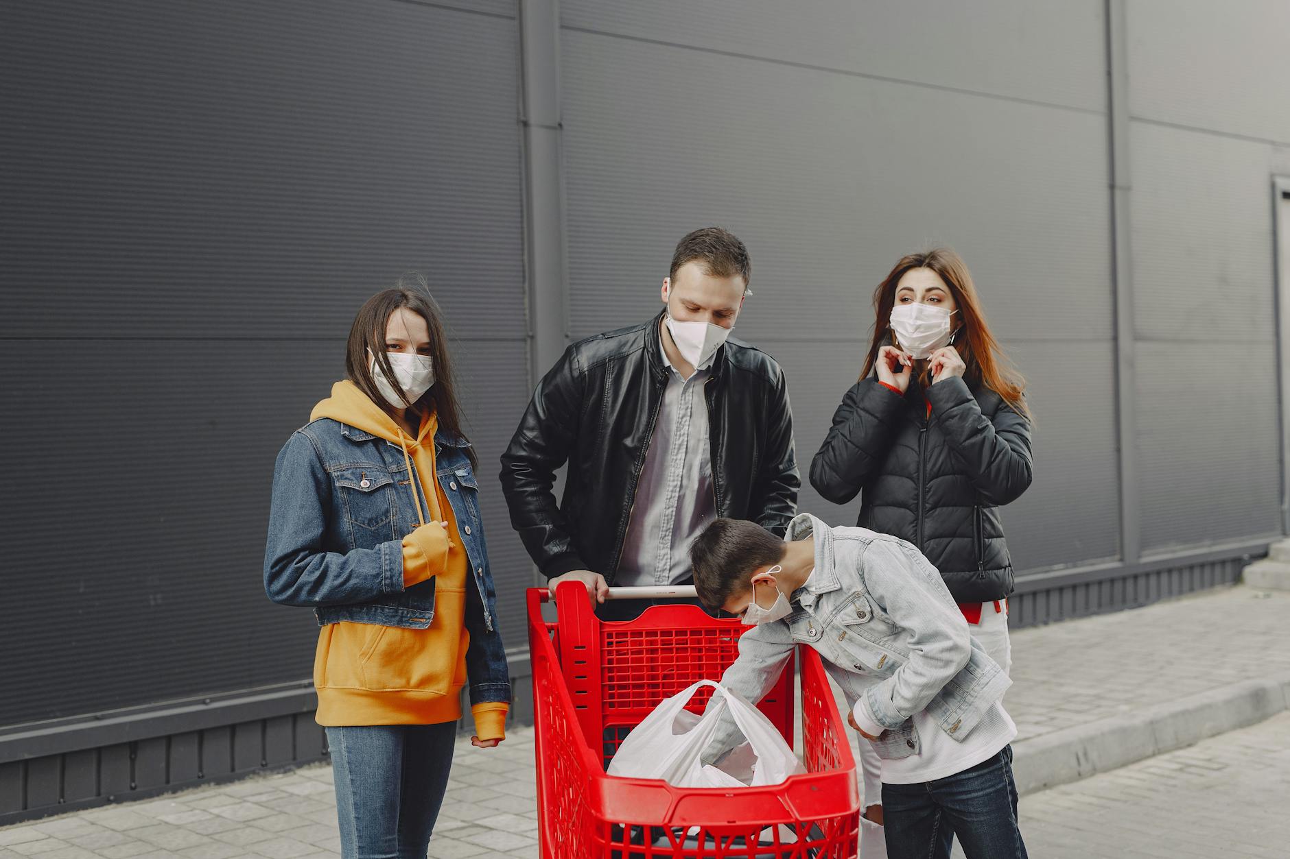 supermercati aperti 2 giugno — Family in casual clothes and protective masks standing on street near supermarket wall with bags of purchases in trolley after shopping