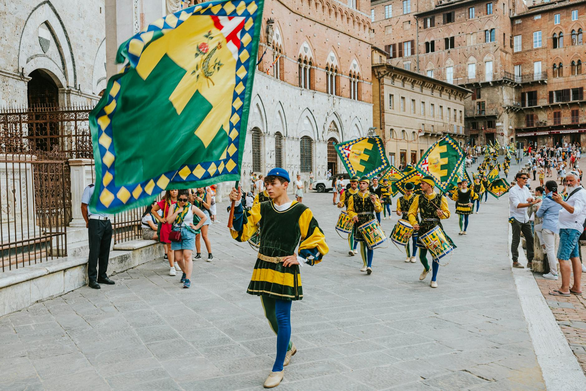 cultura italiana — Traditional flag bearers in a colorful parade in Piazza del Campo, Siena, showcasing rich Italian heritage.