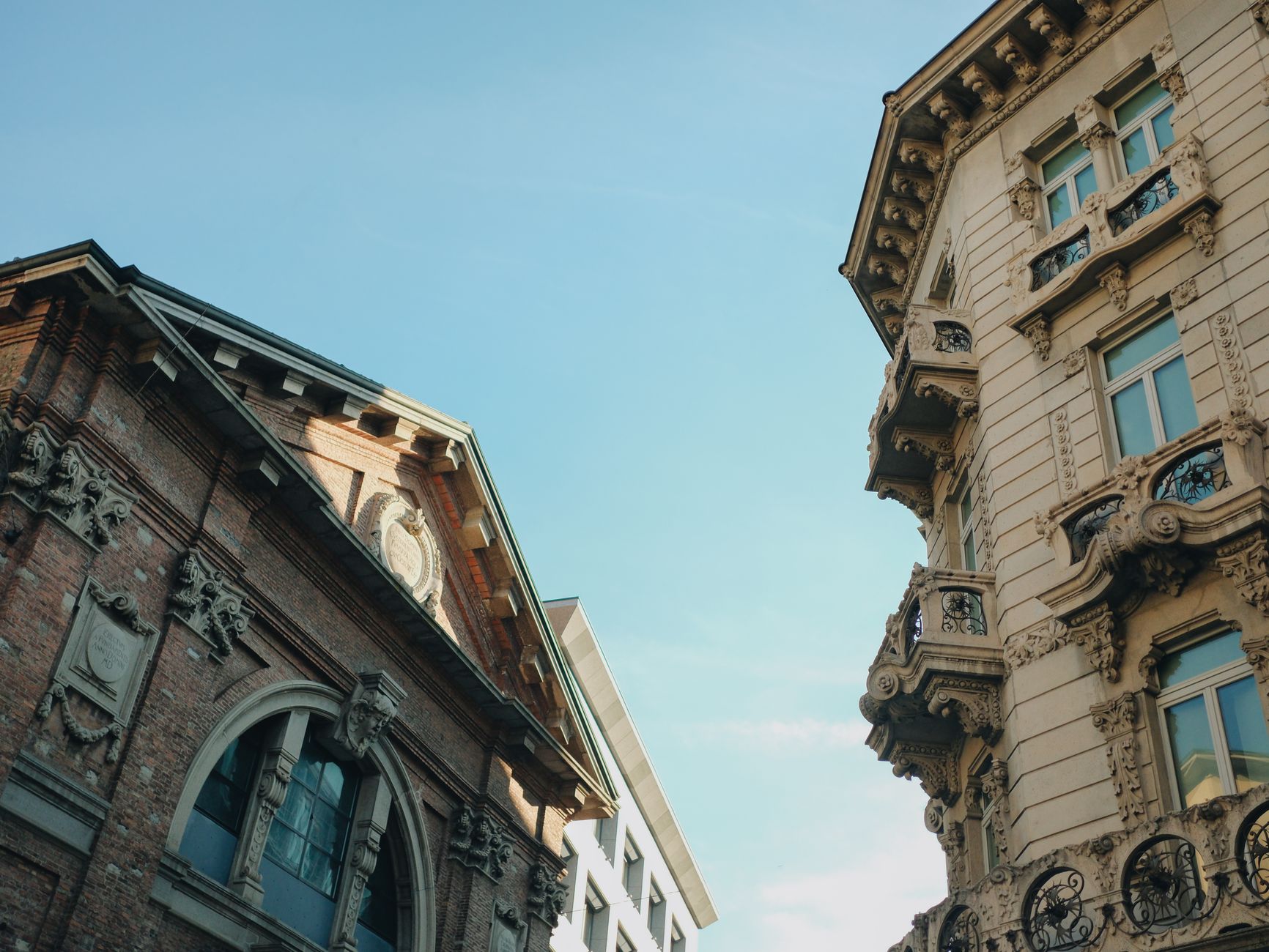costo case Milano — Elegant historic buildings against a clear blue sky in Milan, Italy.