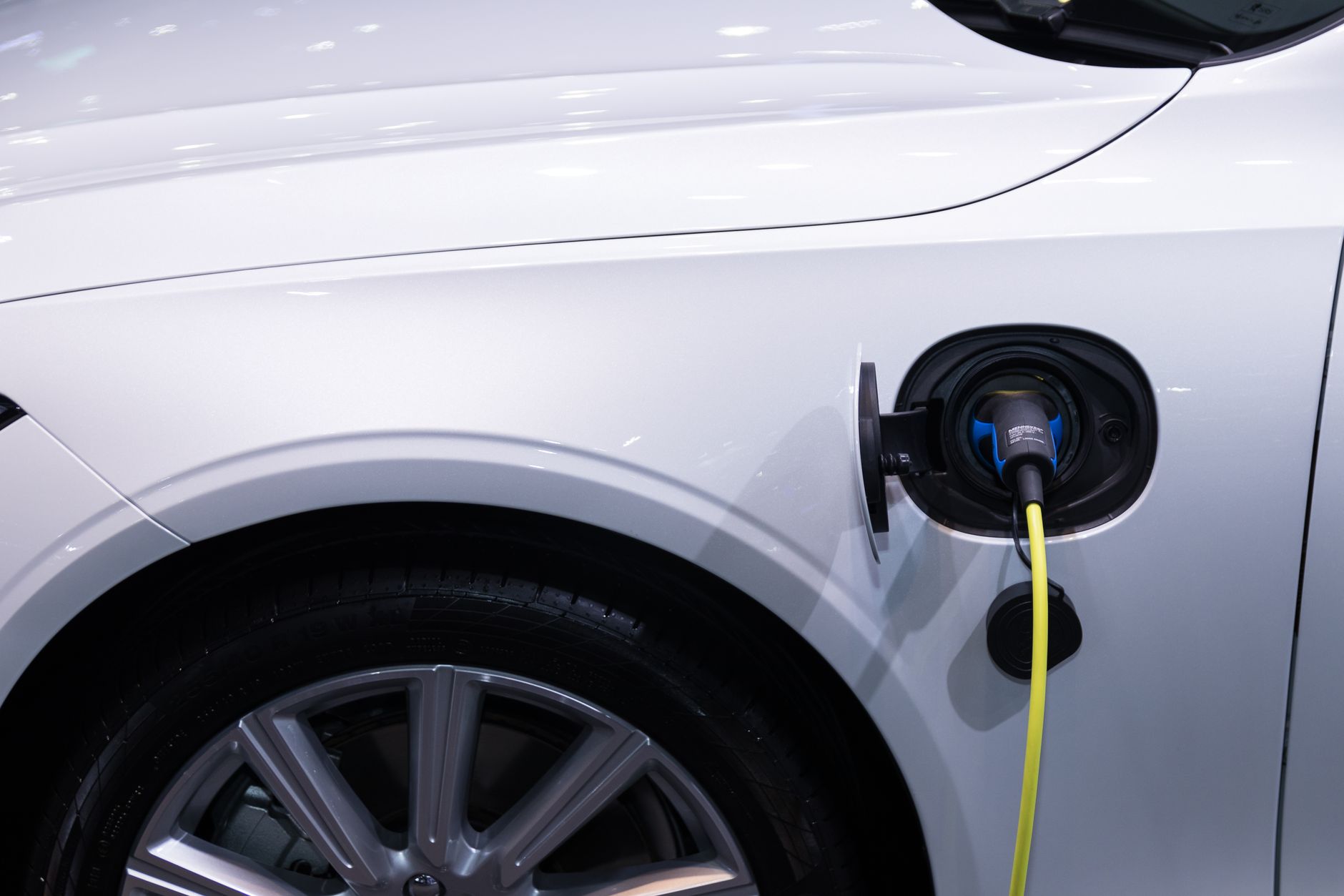 incentivi auto elettriche — A white electric car is plugged in for charging, close-up view of the charging port.