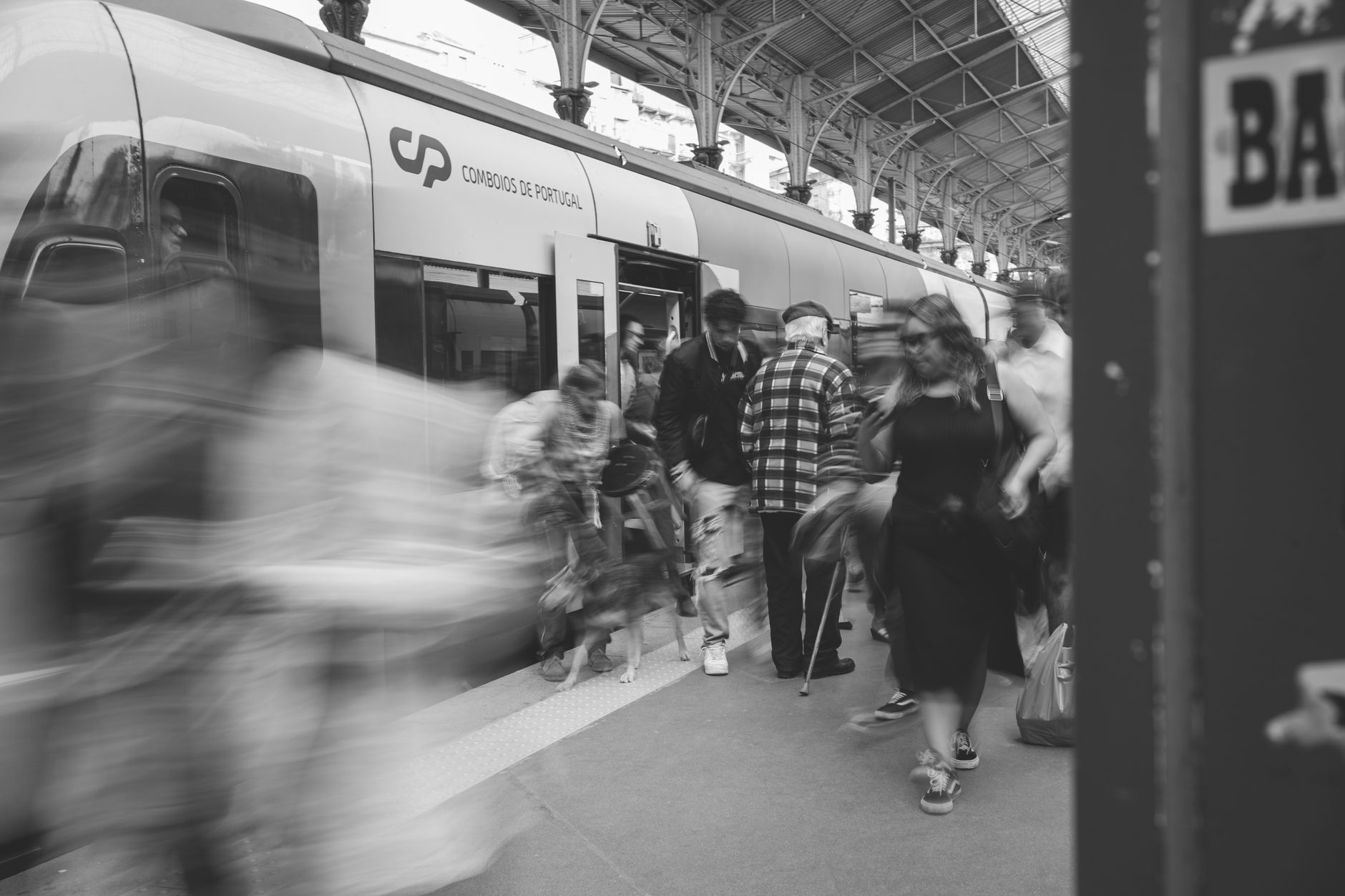 sciopero ferroviario — A black and white scene of commuters at a Lisbon train station, showcasing urban movement.