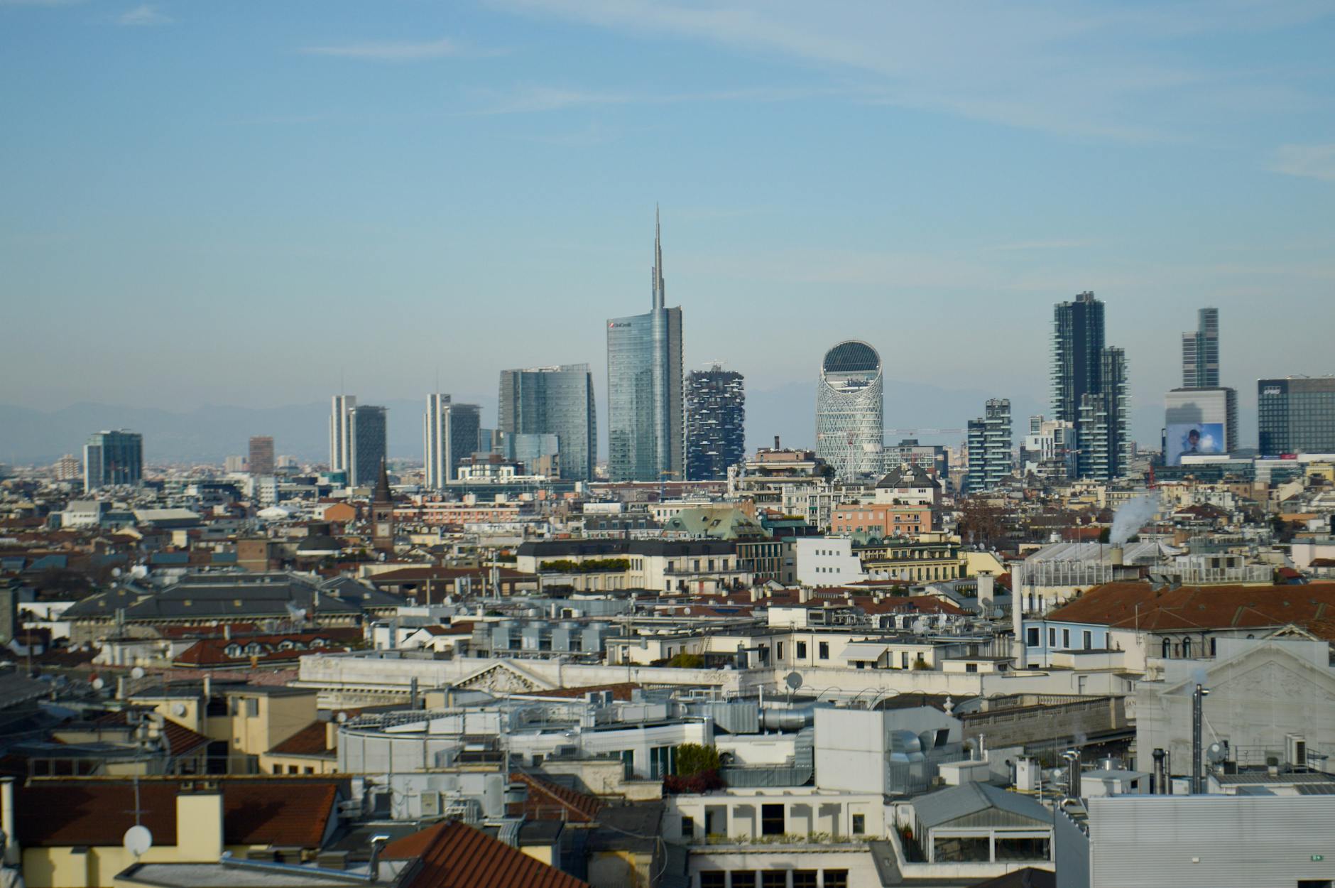 mercato immobiliare — Aerial view of Milan skyline showcasing modern skyscrapers and urban landscape under a clear blue sky.