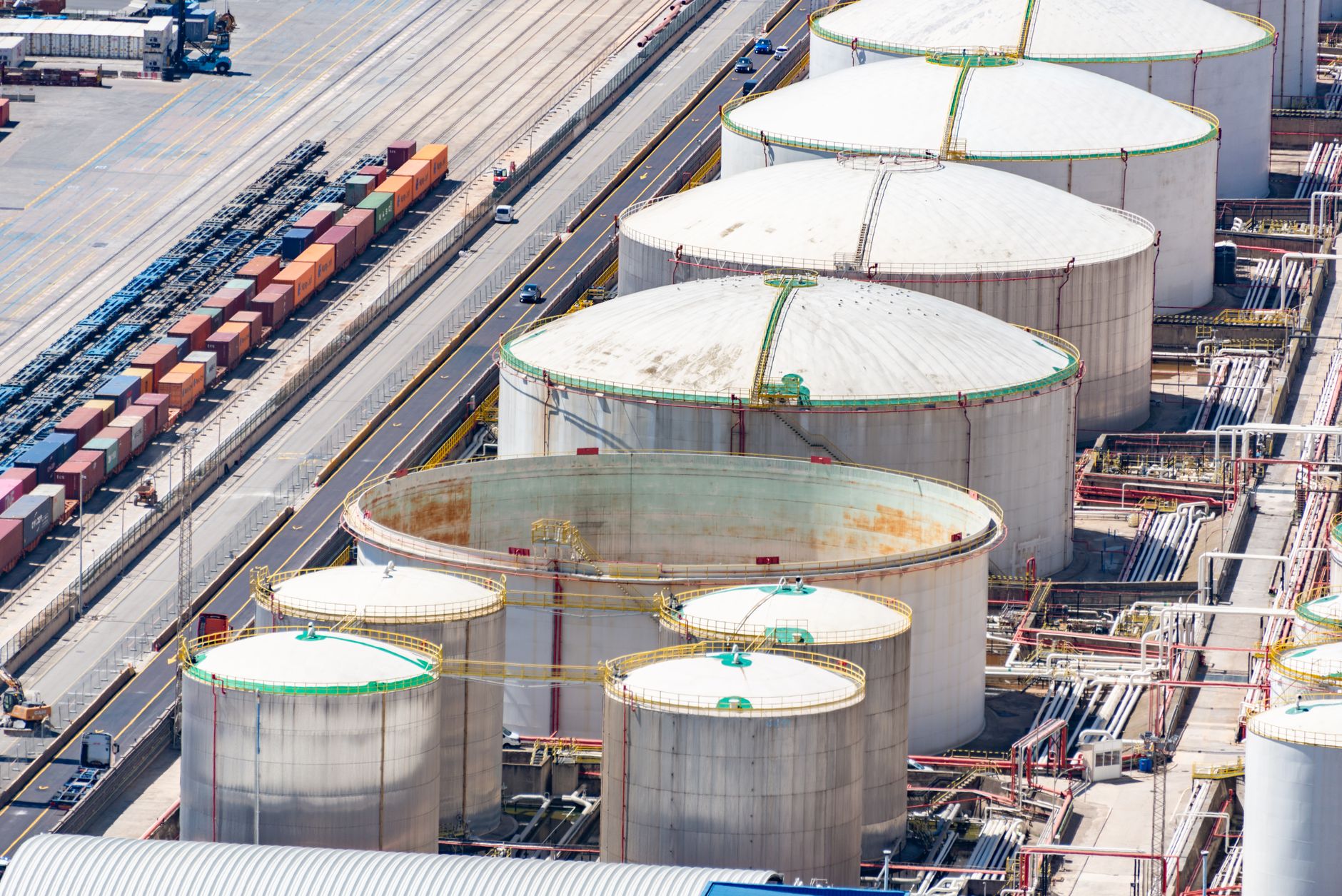 petrolio calo New York — Aerial shot of large oil storage tanks in an industrial district with adjacent railway tracks.