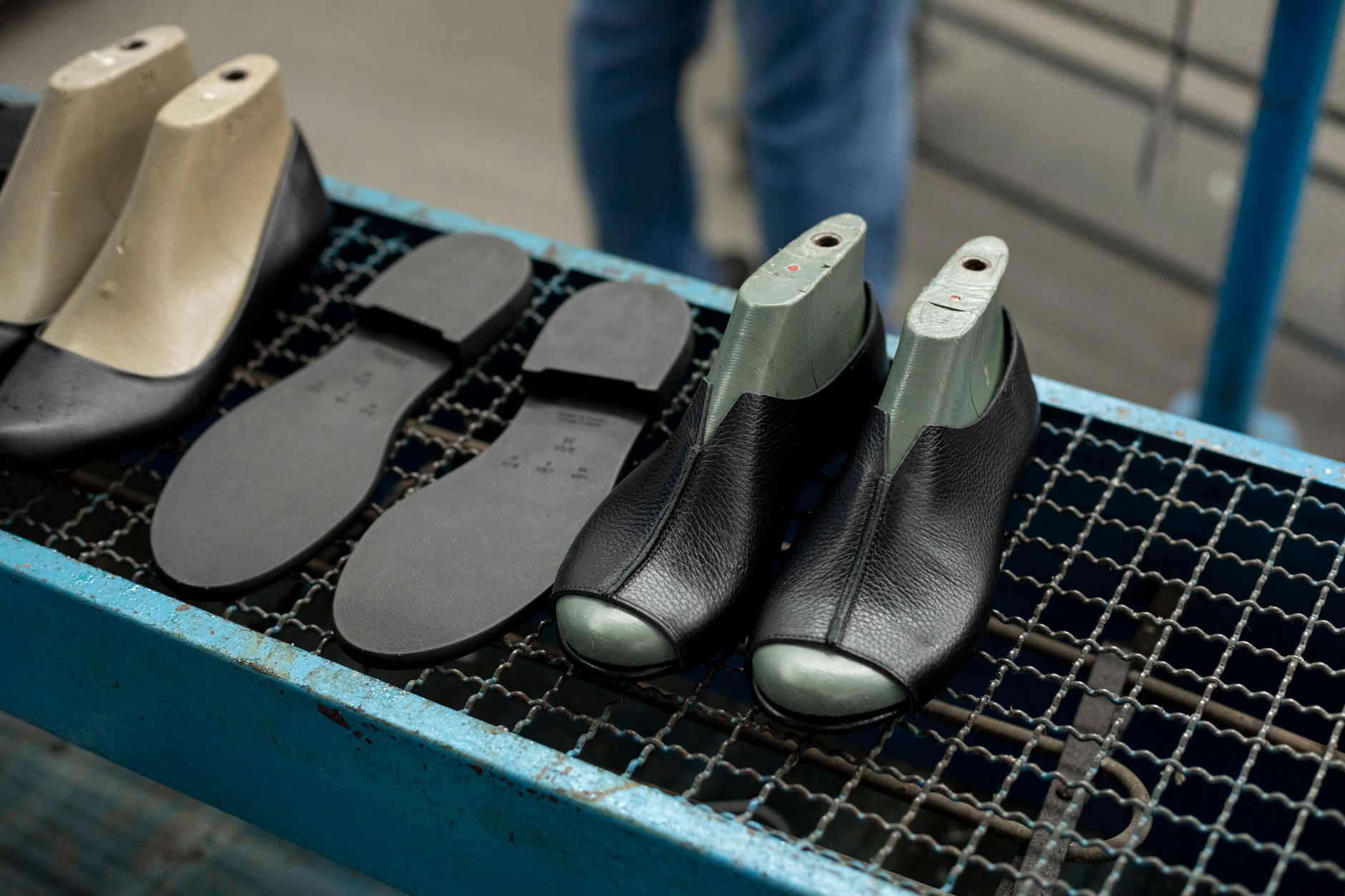 fondi fieristici — Detailed view of shoe making process with leather uppers and molds on work table.