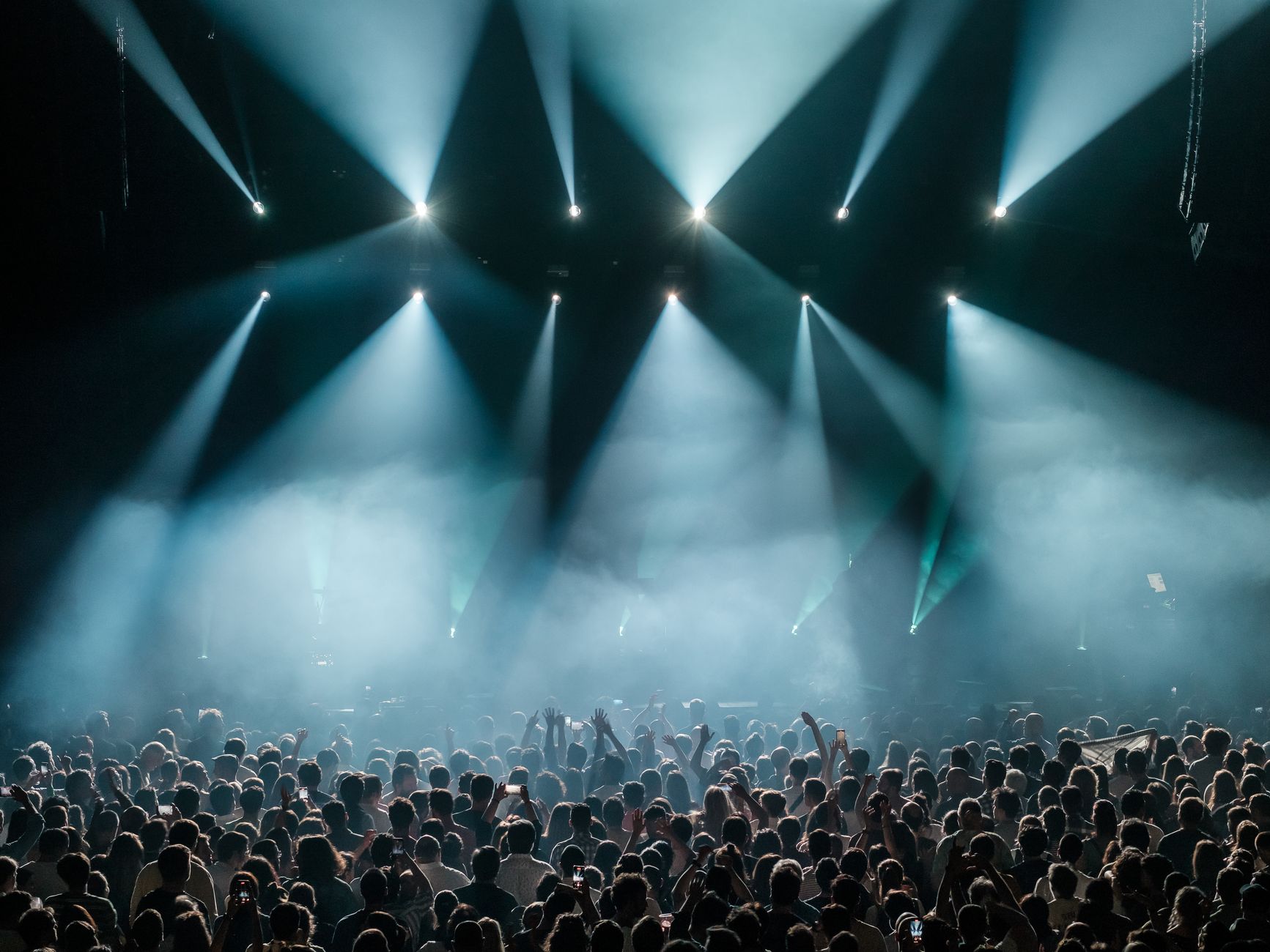 musica fasci luminosi — A dynamic concert scene with a large crowd enjoying vibrant stage lighting and a lively atmosphere.