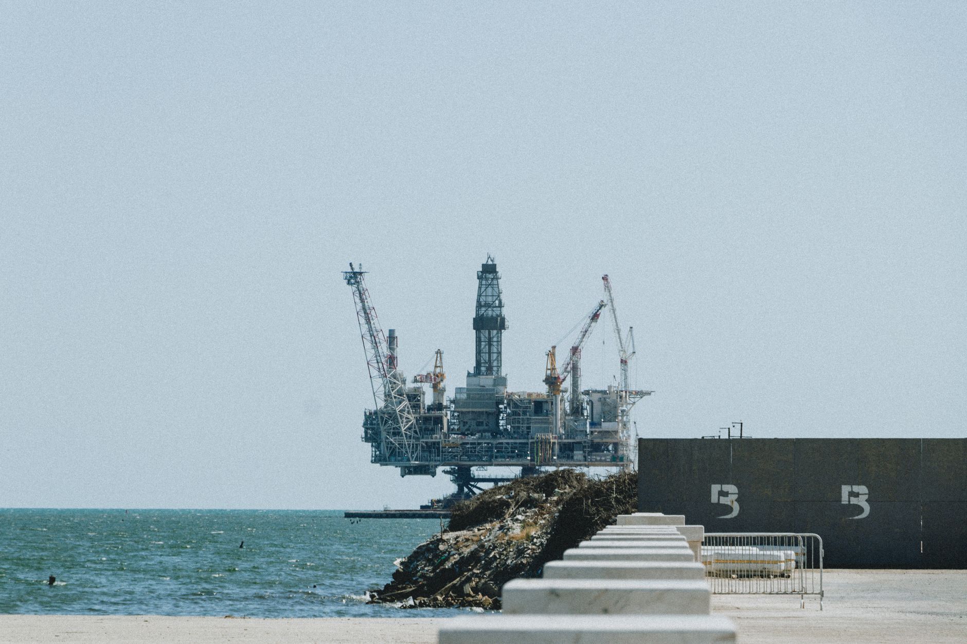 crollo petrolio Usa Iran — Distant view of an offshore oil rig with cranes on a sunny day.