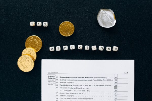 Image of tax deductions concept with coins and tax form on black background.
