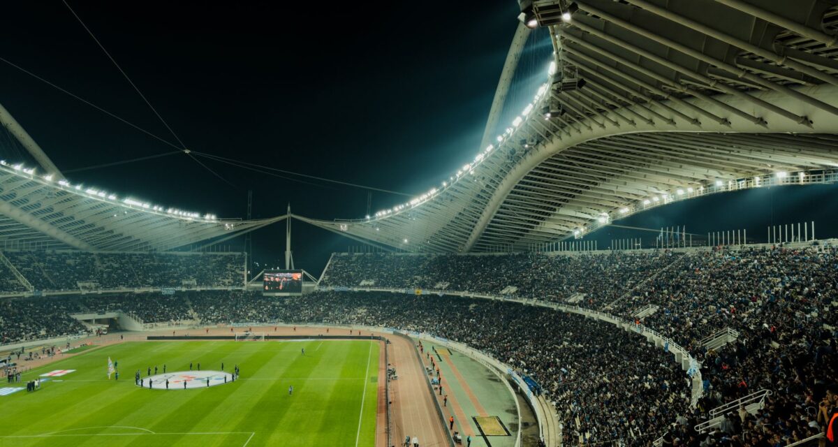A crowded soccer stadium under bright lights at night, capturing the excitement of a live sports event.
