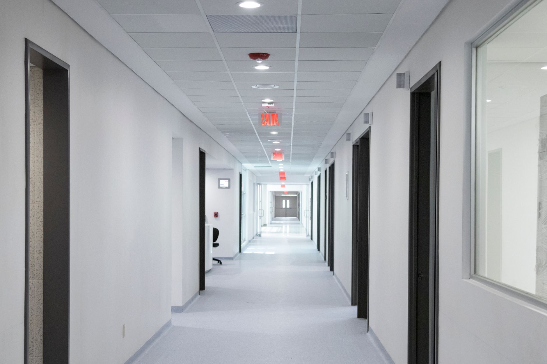 spesa sanitaria — White-walled hospital corridor with modern design and bright overhead lighting.