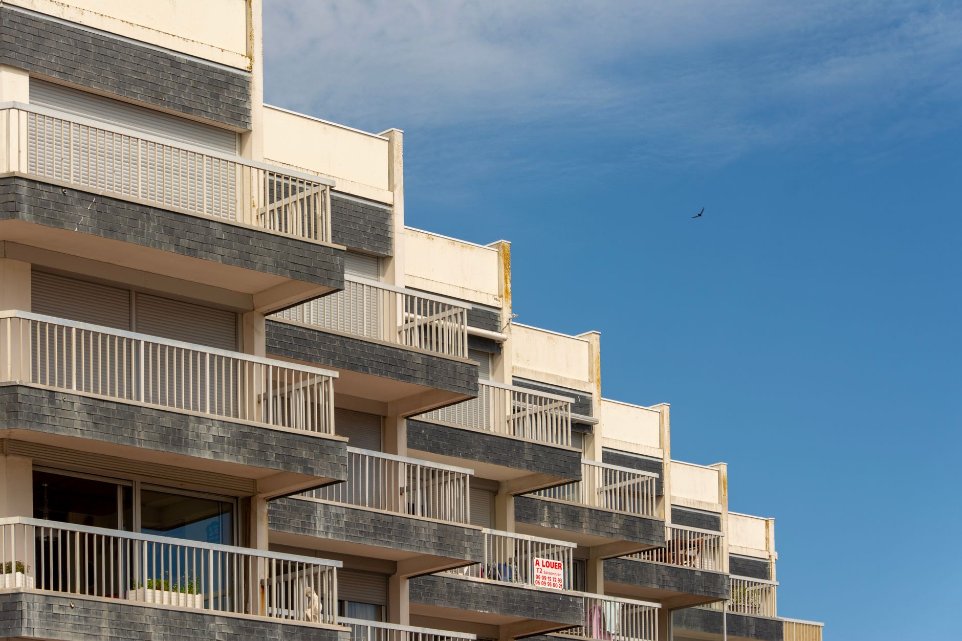 nuove norme UE sugli affitti brevi — A modern apartment building with distinct balconies against a clear blue sky.