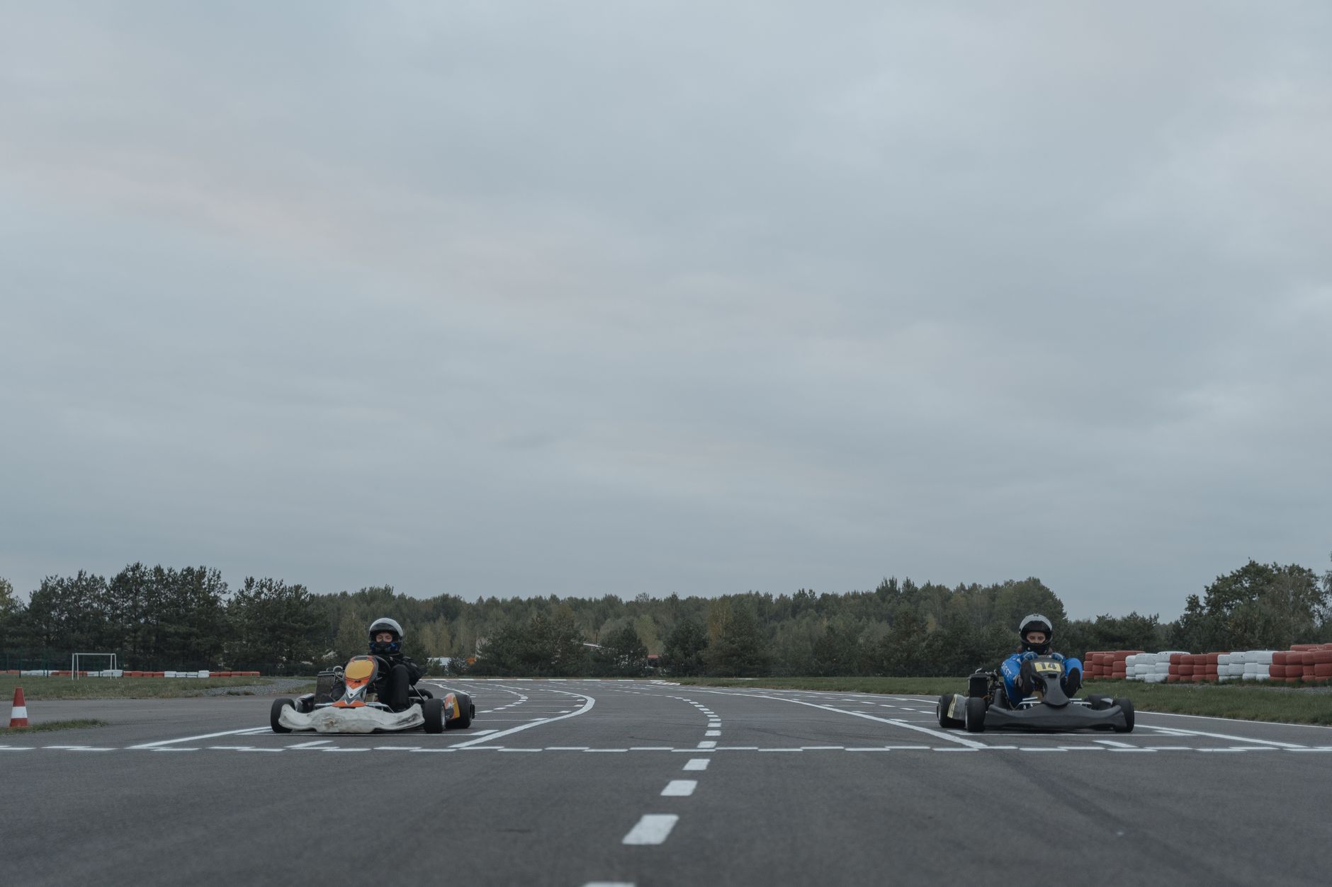 acquisizione LeCont — Two athletes racing go-karts on an outdoor racetrack in overcast conditions.
