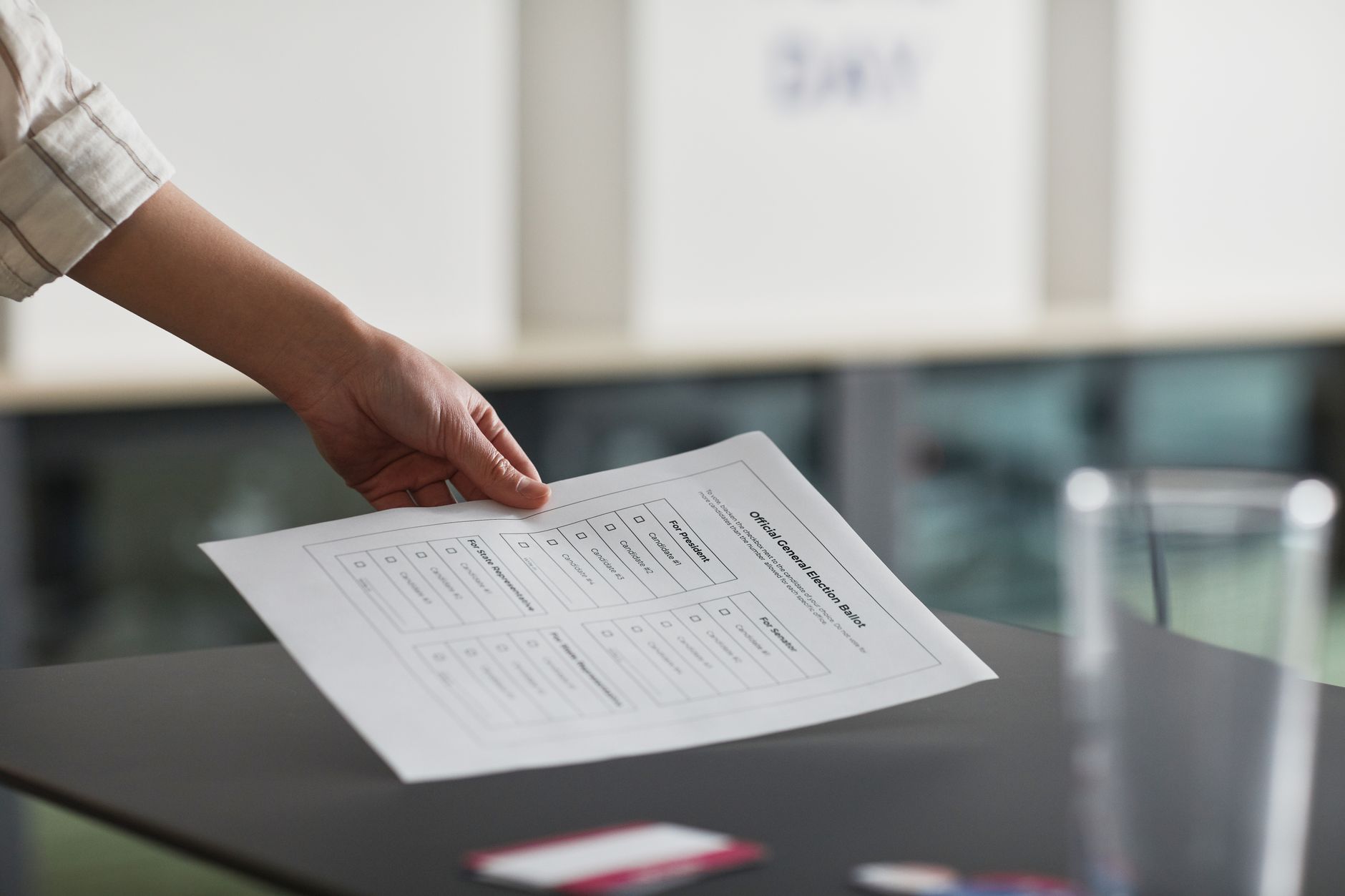 Close-up of a hand holding a ballot paper indoors, symbolizing democracy and civil rights.